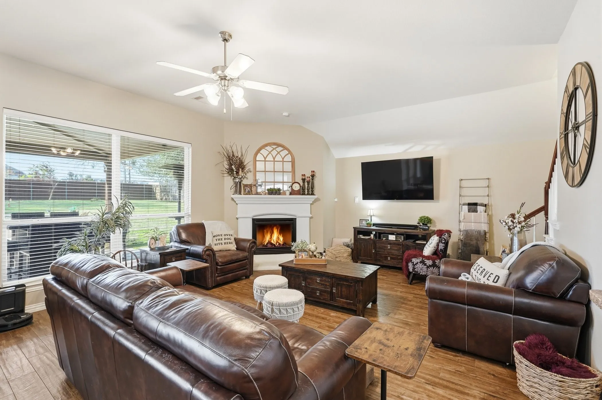 Living area with a ceiling fan, a warm lit fireplace, hardwood / wood-style floors, and lofted ceiling