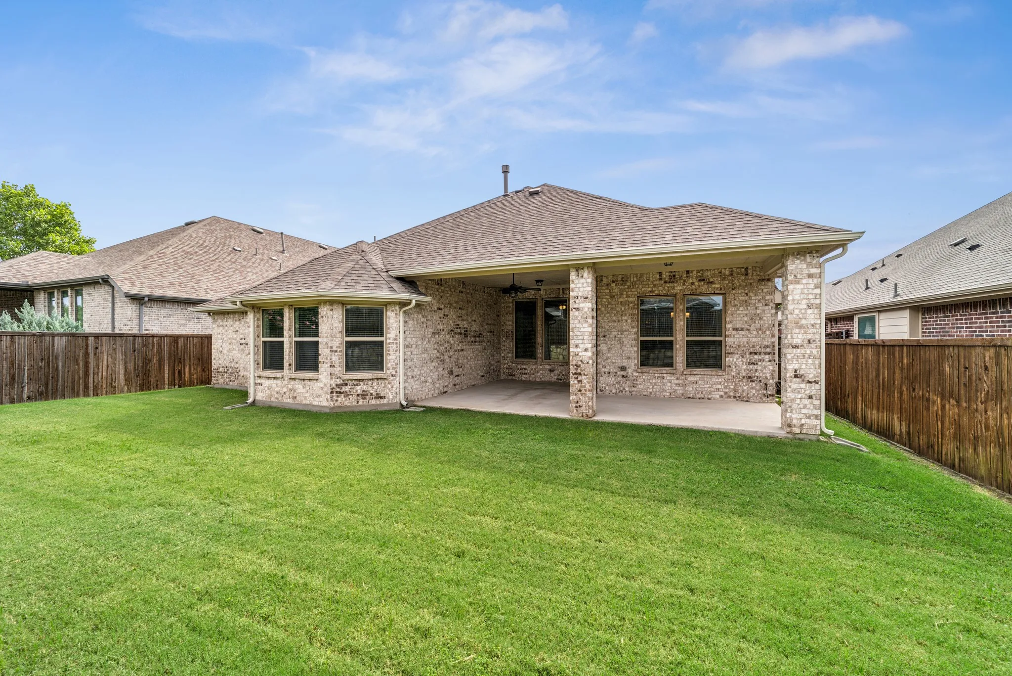 Rear view of property with a patio area, brick siding, a shingled roof, and a fenced backyard