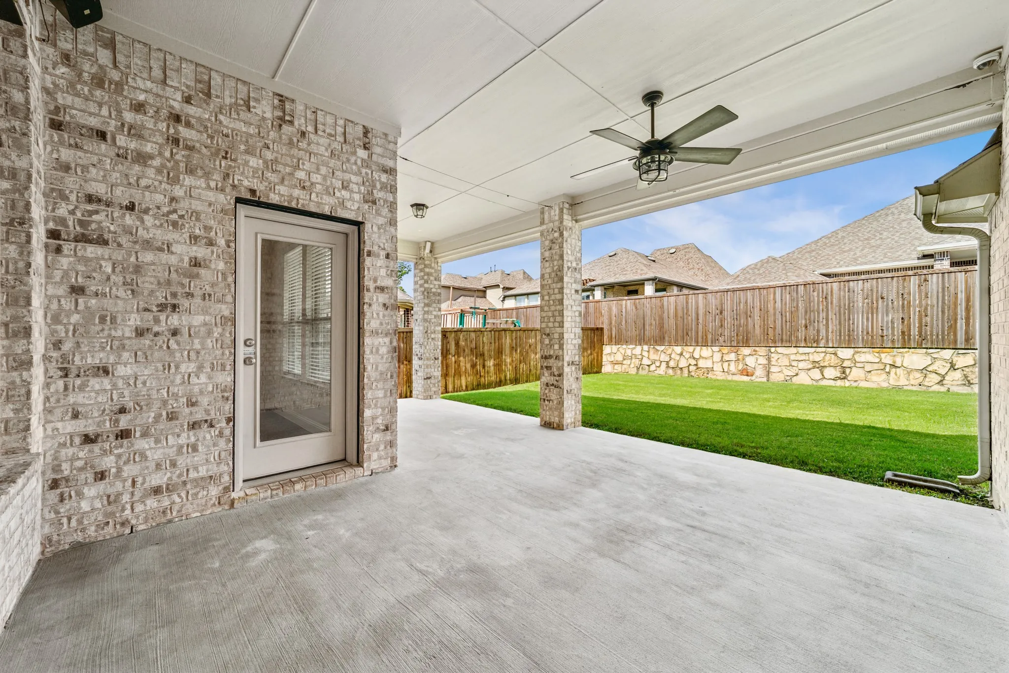 Fenced backyard with a patio, a ceiling fan, and a residential view