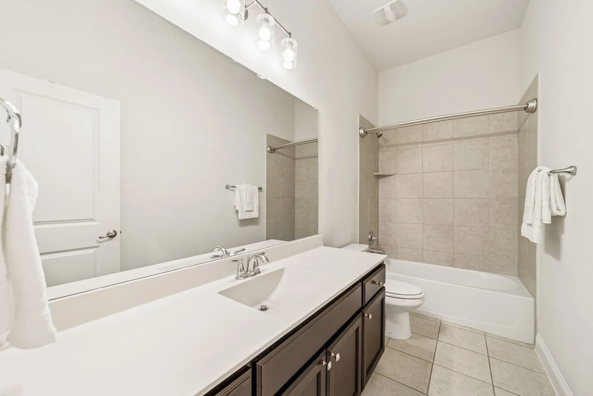 Bathroom featuring shower / washtub combination, vanity, and light tile patterned floors