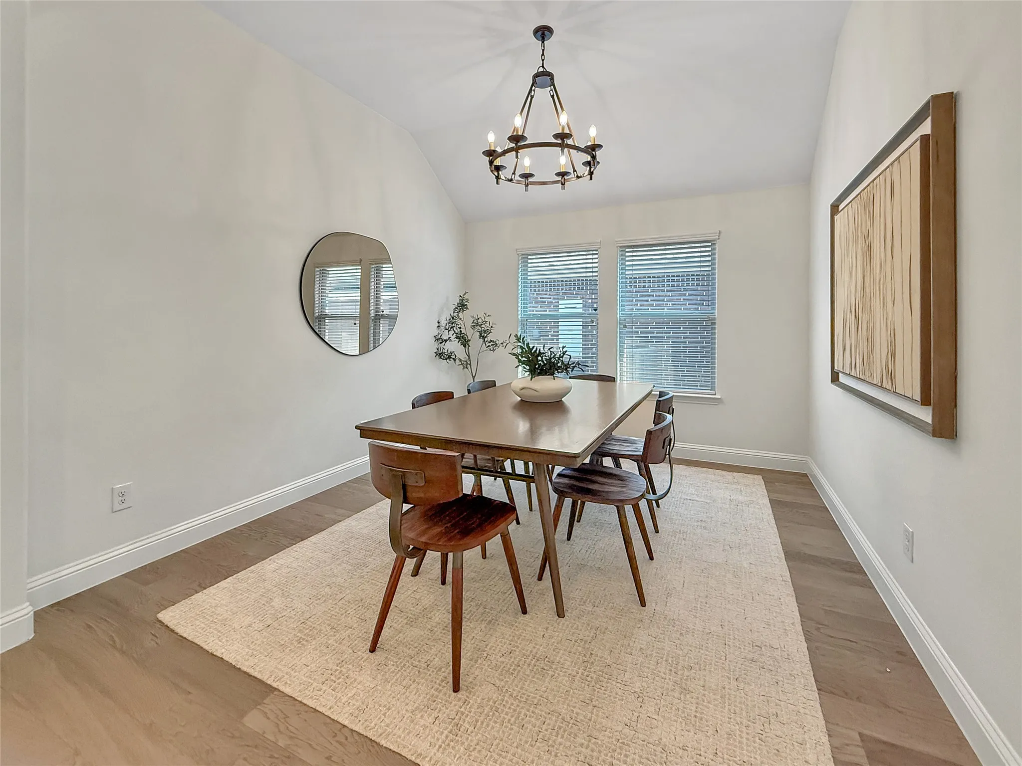 Dining room with vaulted ceiling, light wood-type flooring, and a chandelier