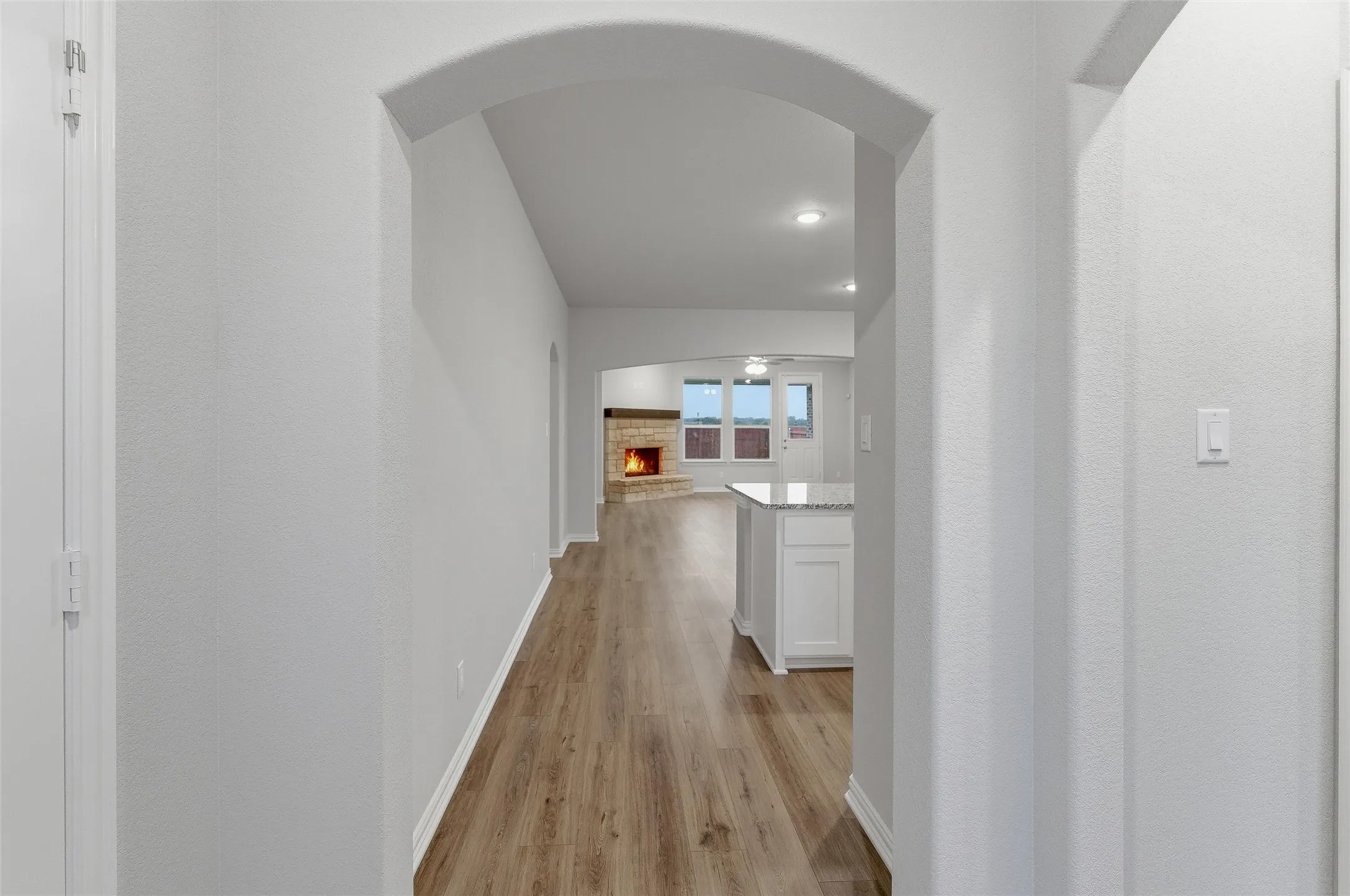 Archway entry opening to an expansive interior with wood-finish flooring
