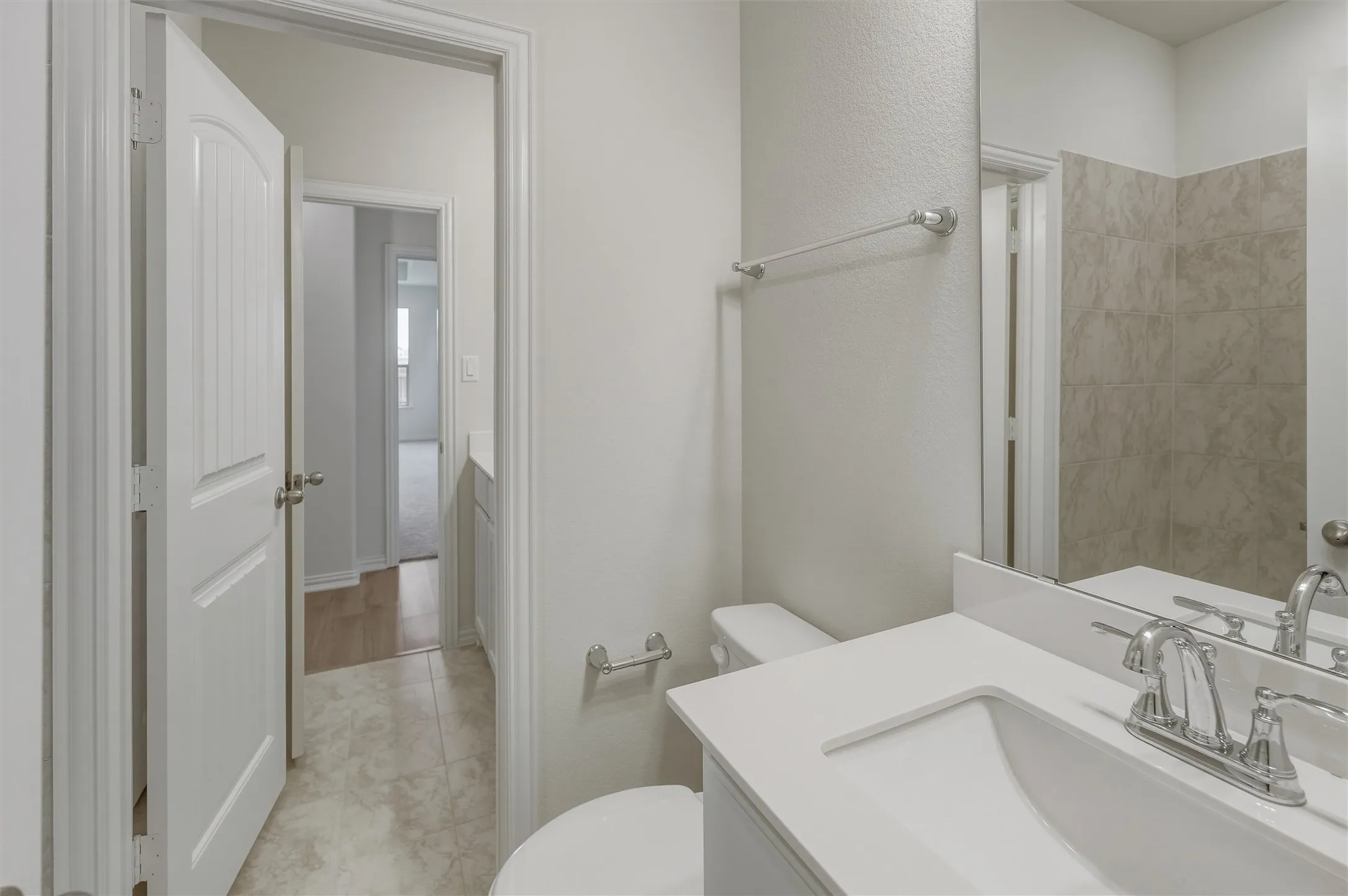Bathroom featuring a white vanity with an integrated sink, polished chrome faucet, and a large mirror