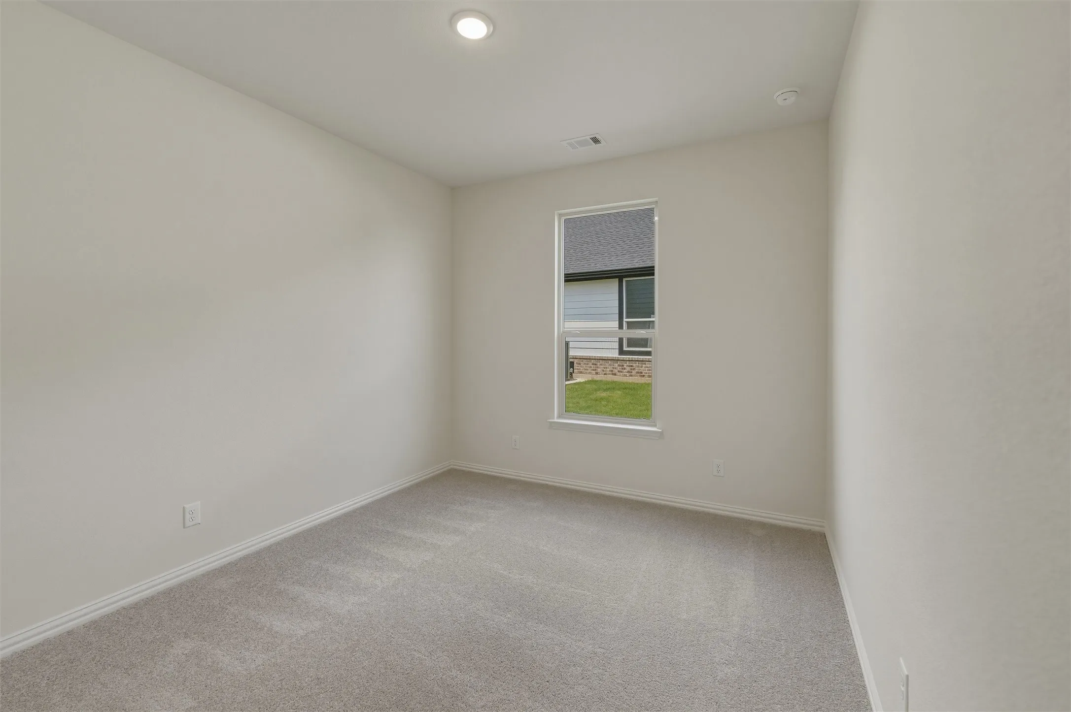 Neutral painted walls featuring a single window and recessed lighting