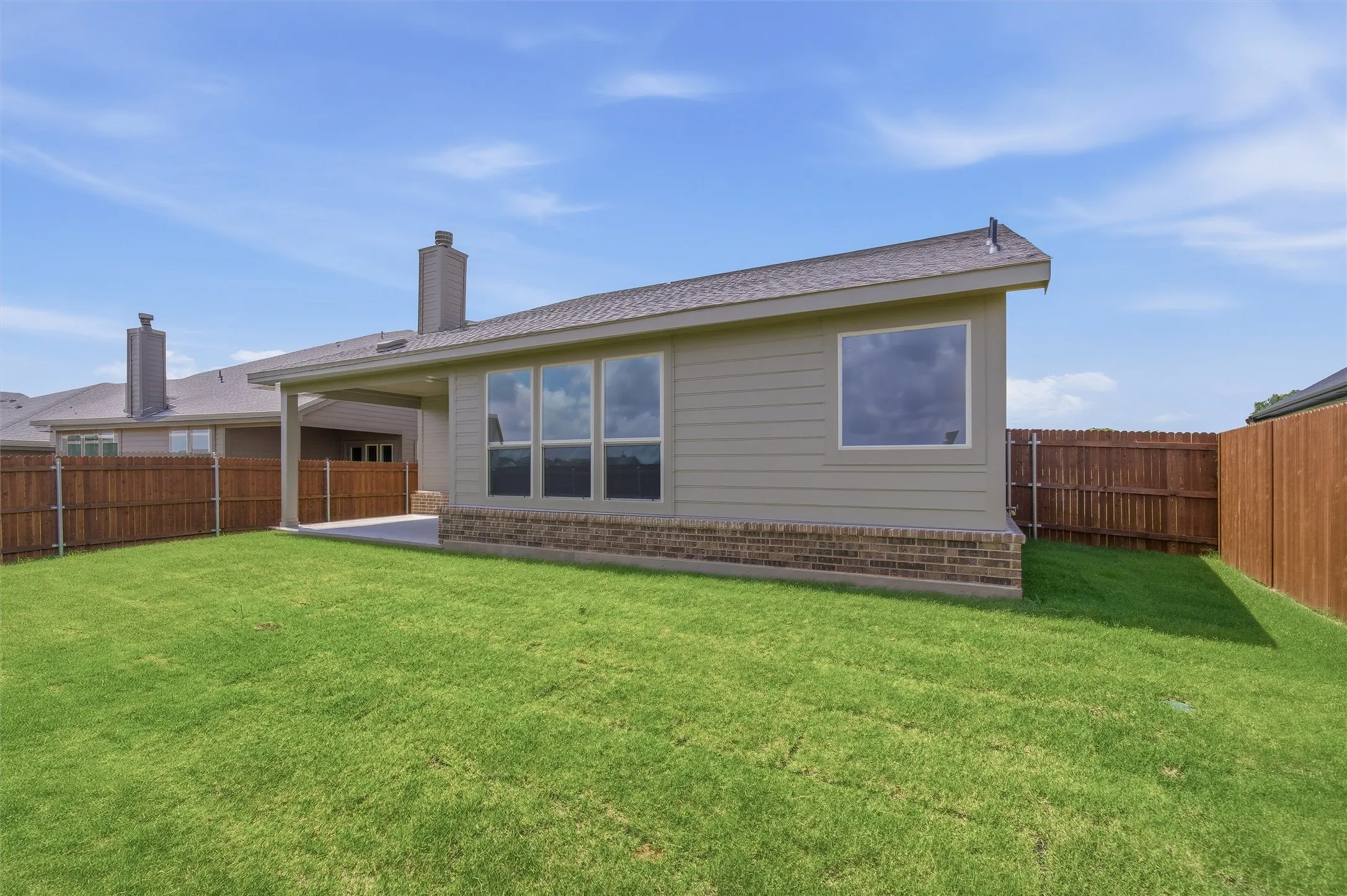 Expansive backyard featuring a manicured lawn, full privacy fencing, and a concrete patio