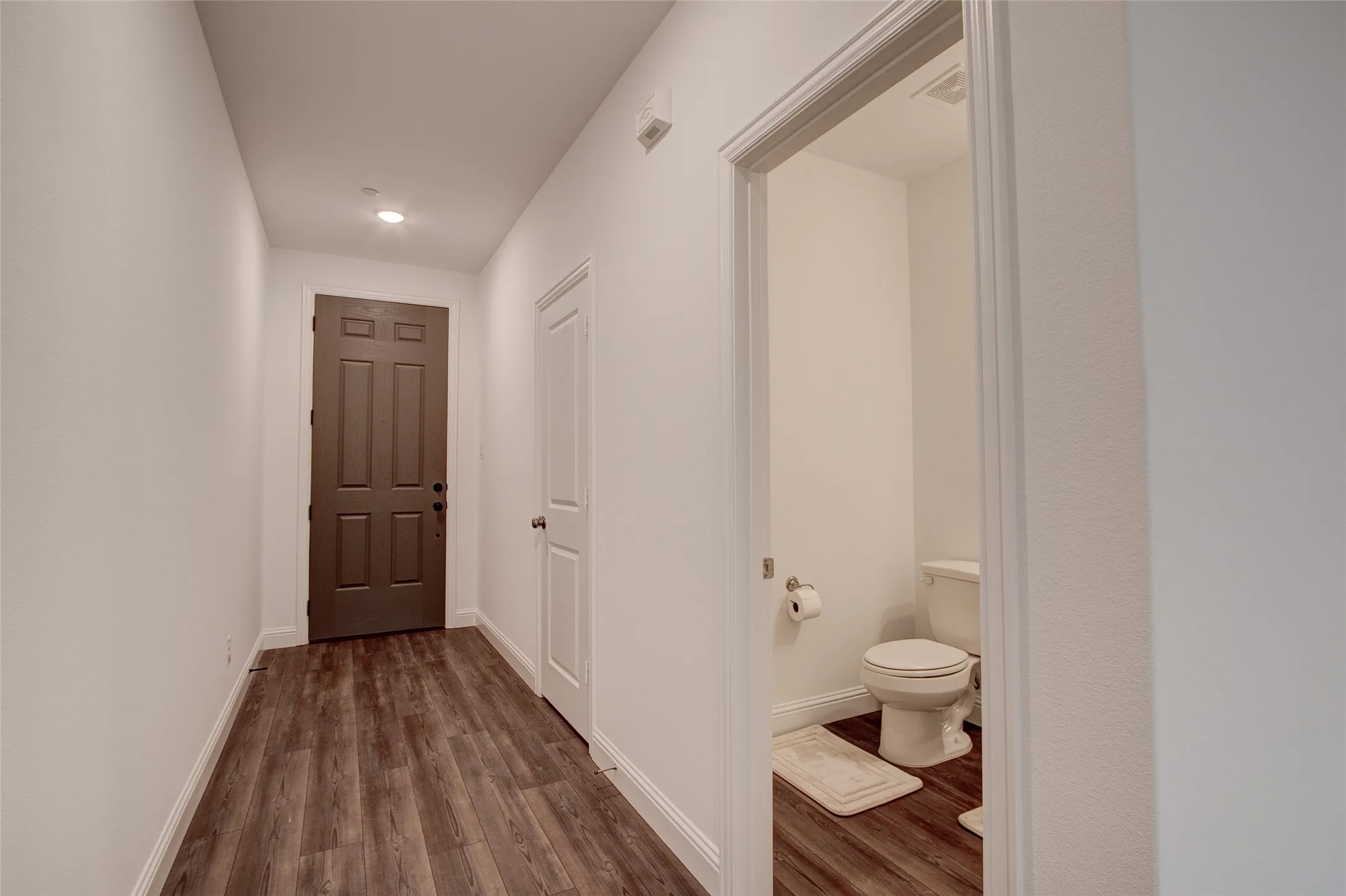 Corridor with dark wood-type flooring and recessed lighting