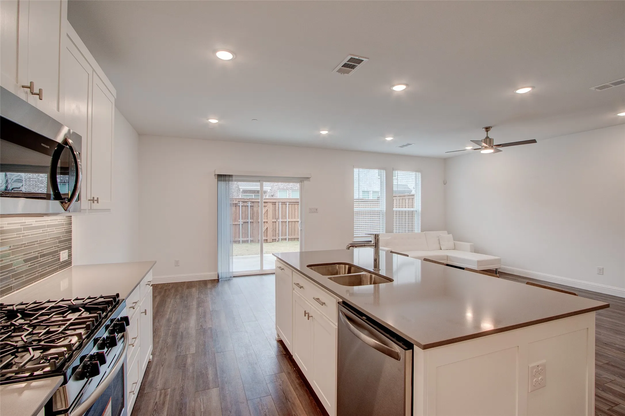 Kitchen with white cabinetry, a kitchen island with sink, stainless steel appliances, dark wood-type flooring, and recessed lighting