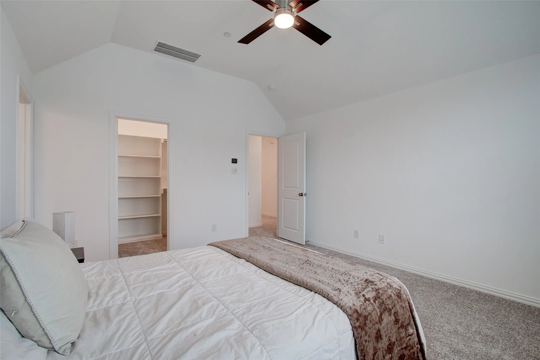 Carpeted bedroom with a walk in closet and a ceiling fan