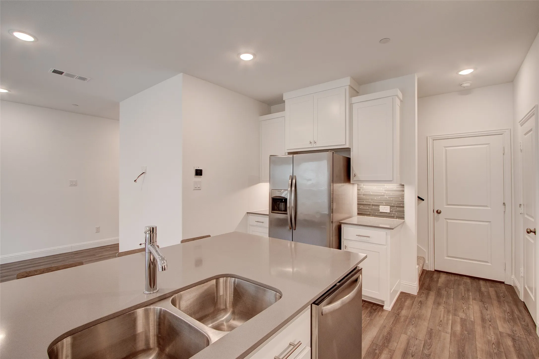 Kitchen with stainless steel appliances, white cabinets, light wood-style floors, recessed lighting, and light stone counters