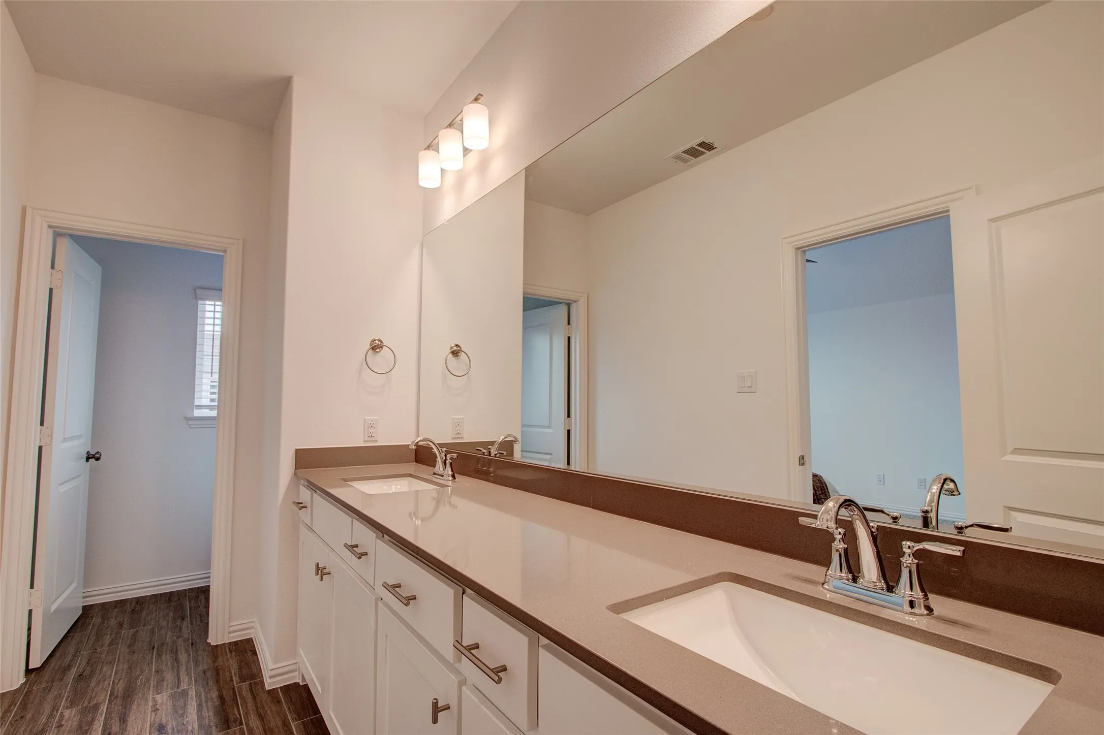 Bathroom with double vanity and dark wood-style floors