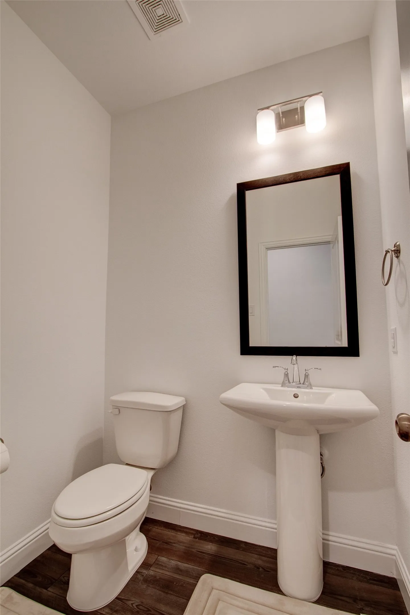 Half bath with dark wood-type flooring and baseboards