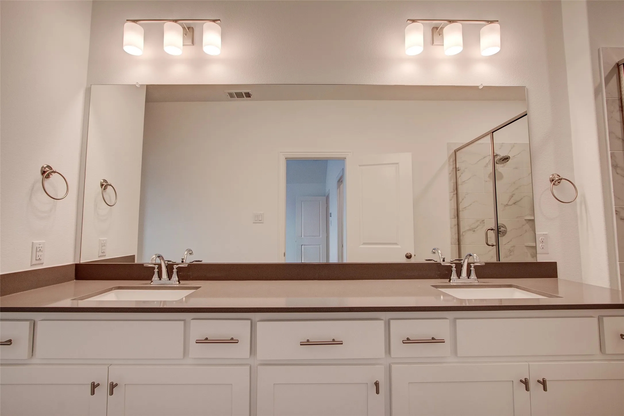 Full bath featuring double vanity and a marble finish shower