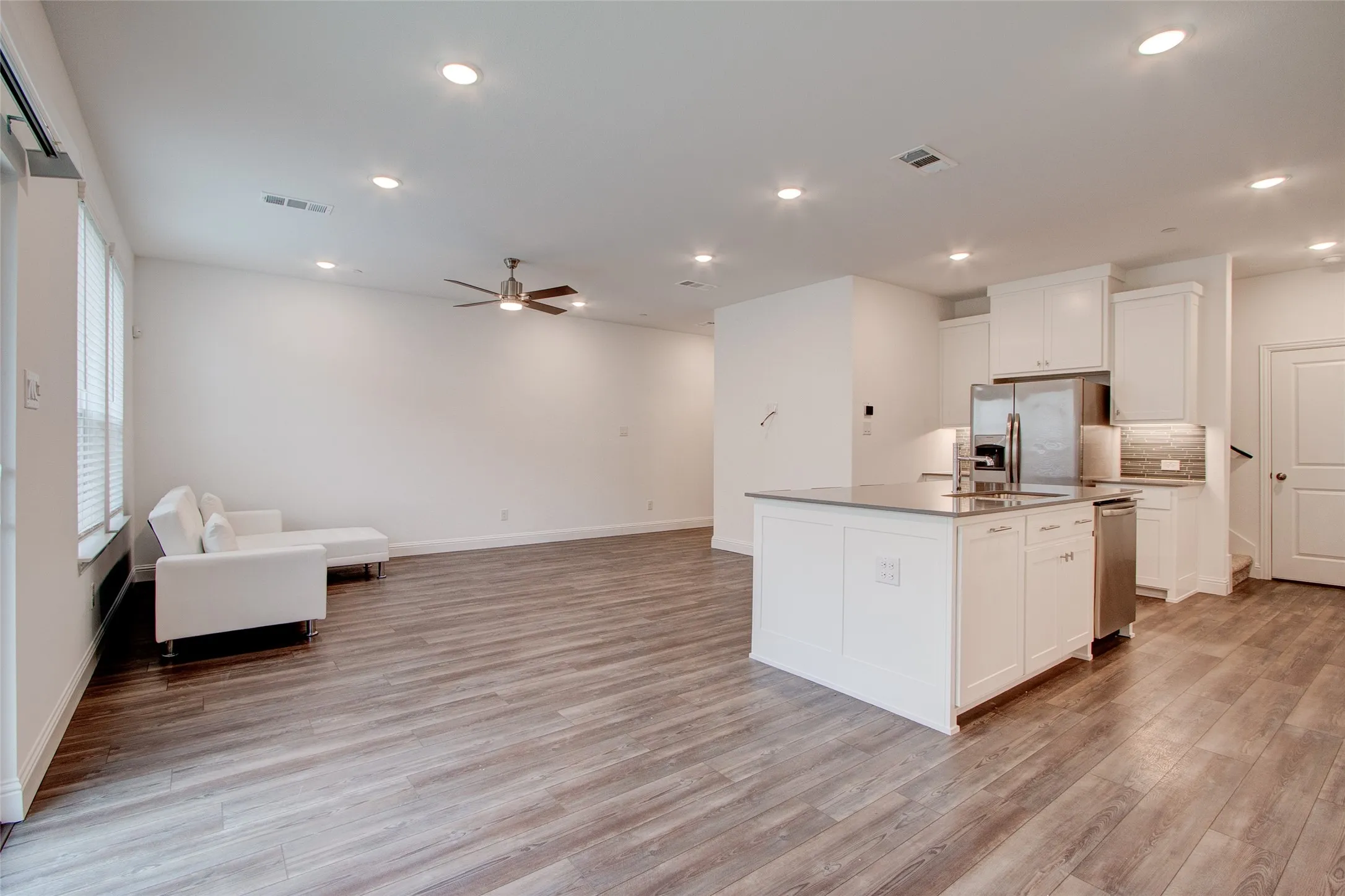 Kitchen with white cabinetry, open floor plan, an island with sink, stainless steel appliances, and recessed lighting