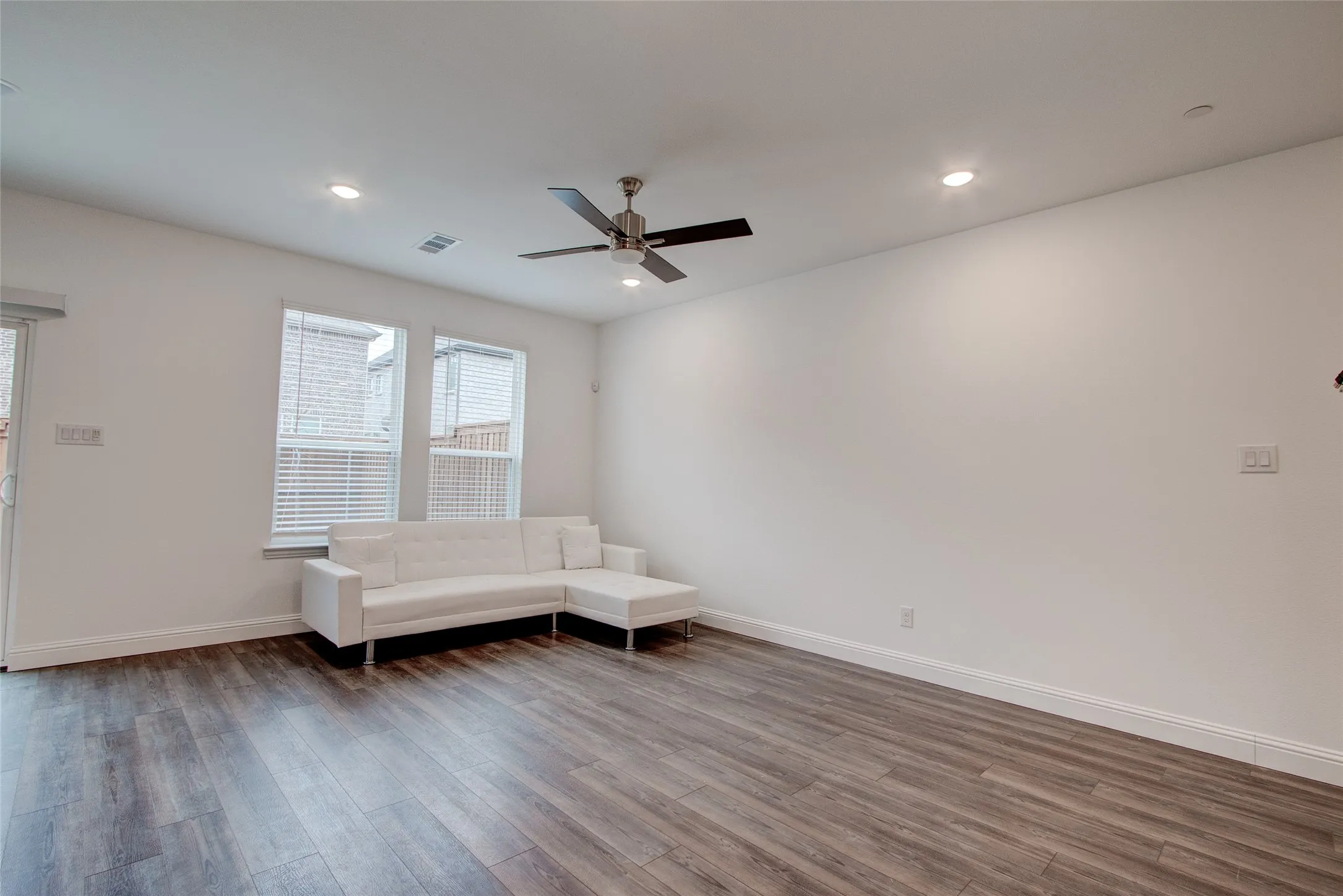Living area with dark wood-style flooring, a ceiling fan, and recessed lighting