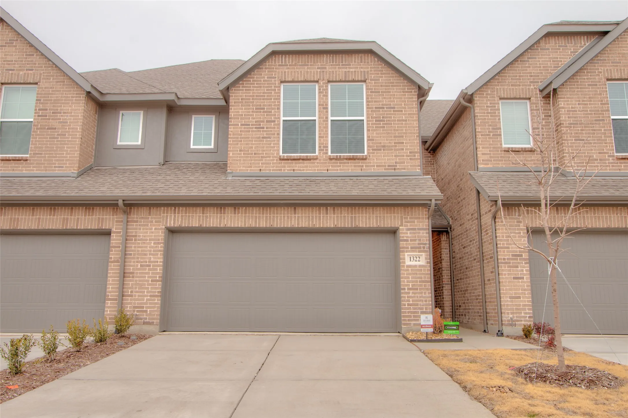 Craftsman inspired home with roof with shingles, driveway, brick siding, and an attached garage