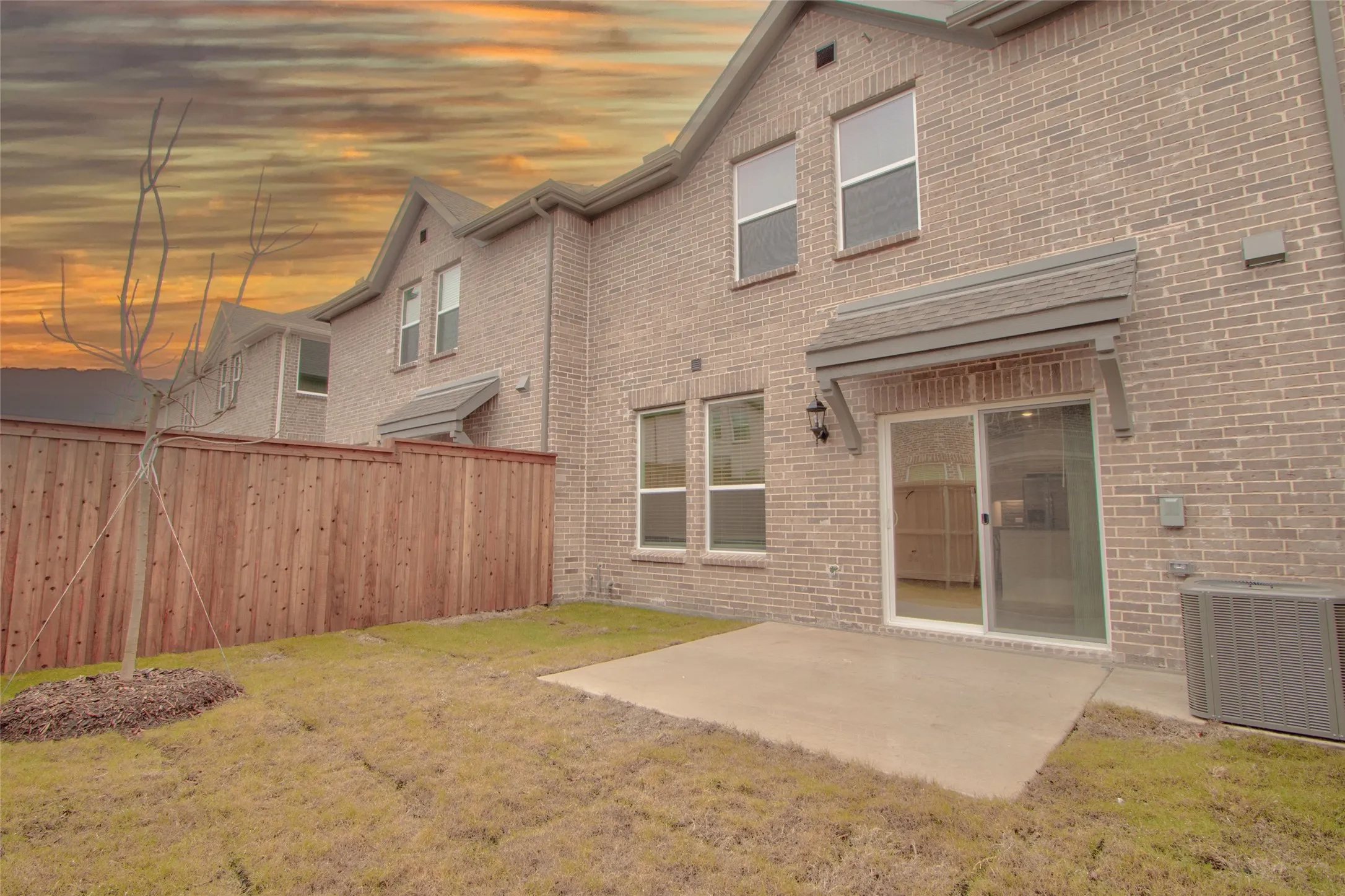 Back of house at dusk with a patio area and brick siding