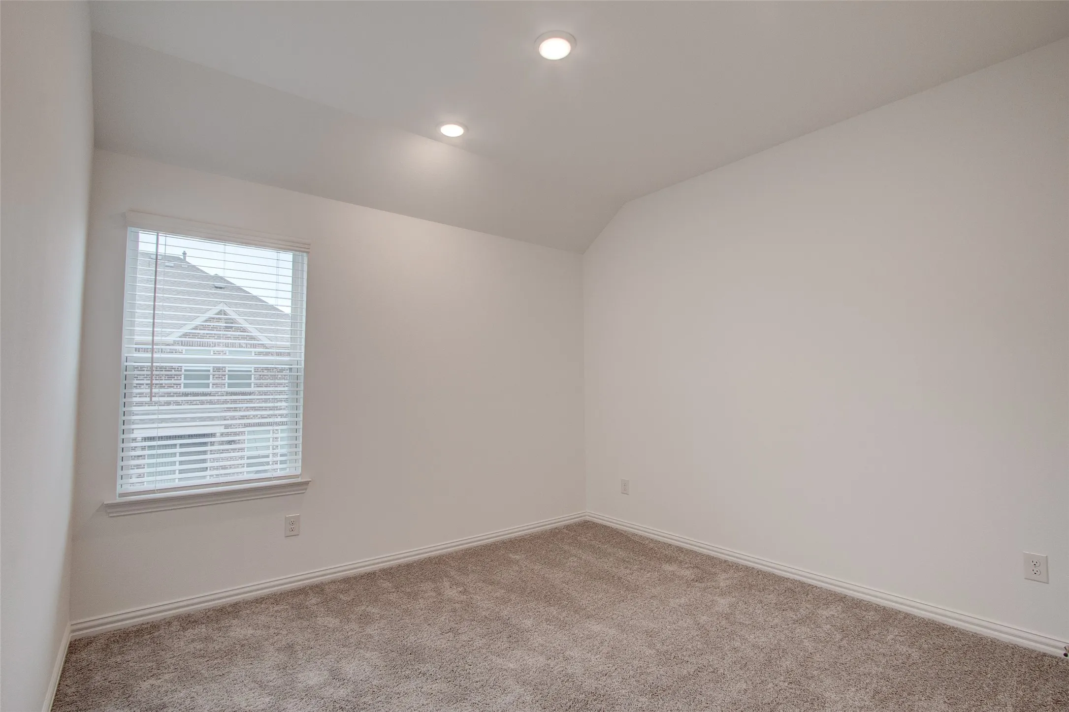 Carpeted empty room with vaulted ceiling and recessed lighting