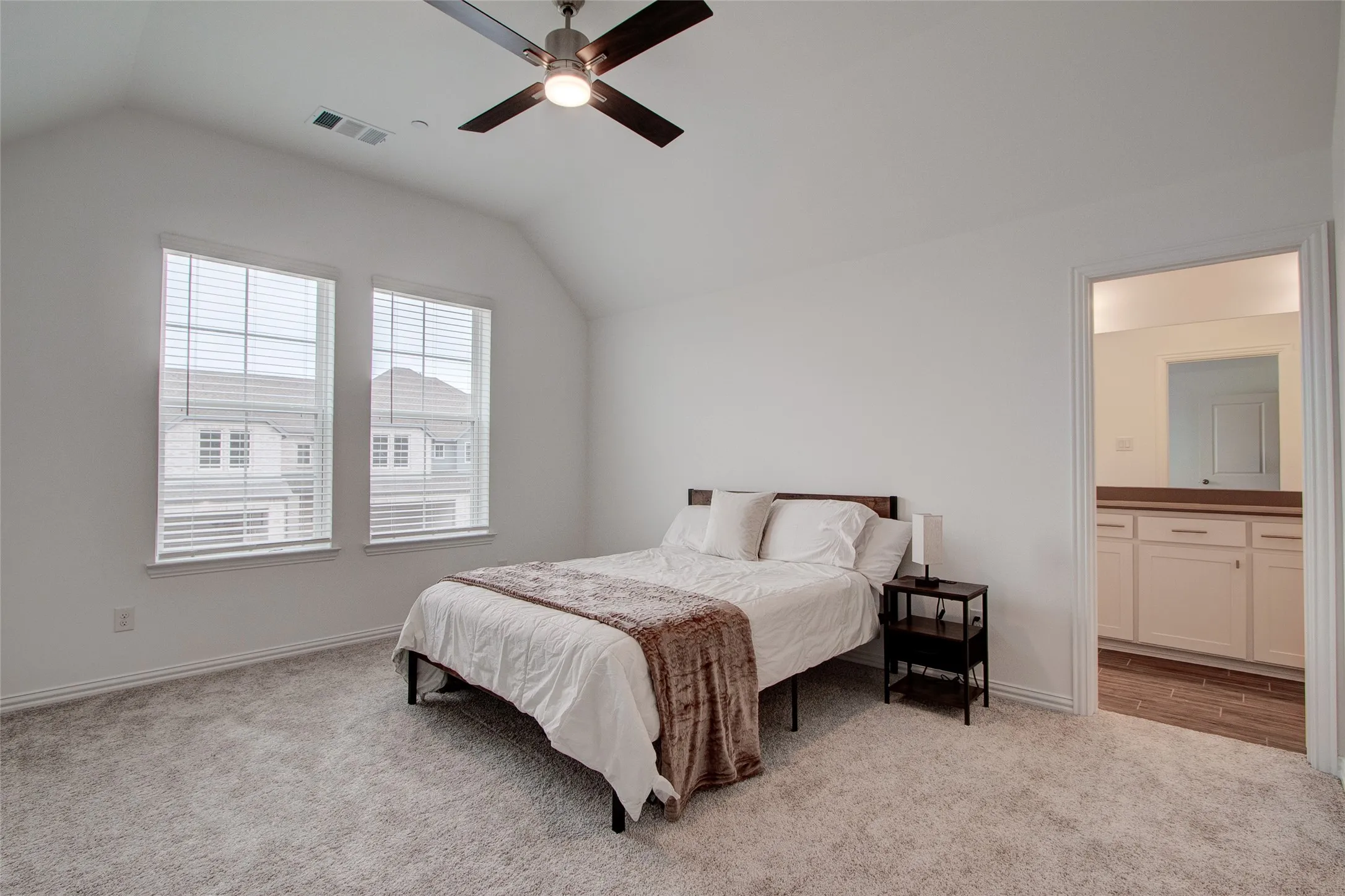 Bedroom with light colored carpet, ensuite bathroom, and ceiling fan