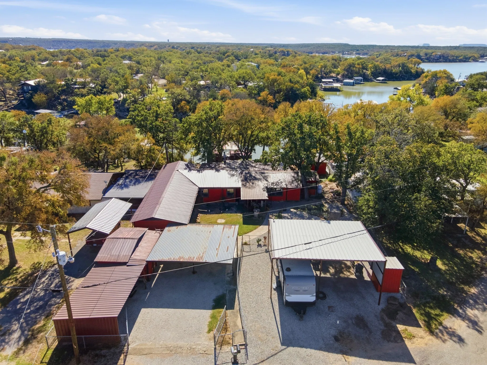 Aerial view showing the residence, parking and outbuildings.