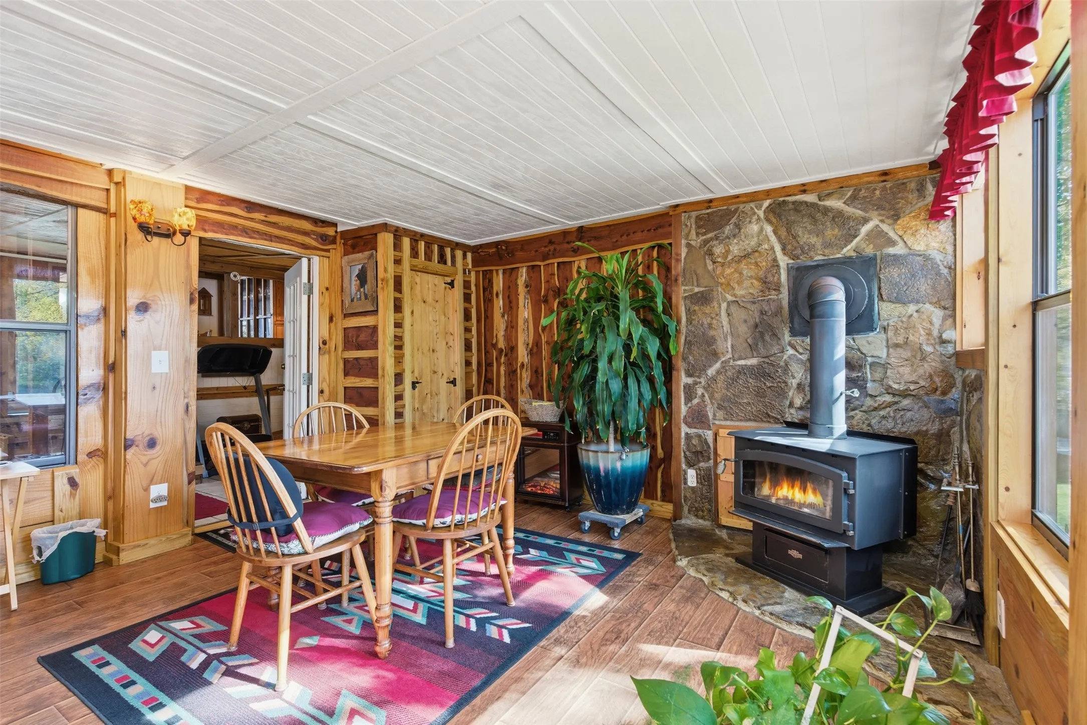 Lake-facing sunroom with wood-burning stove and walls of windows overlooking the lake.