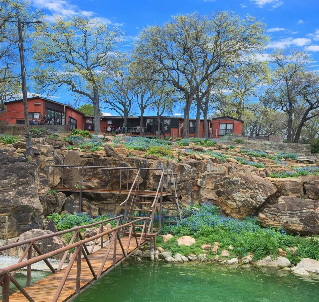 View from the water showing the elevated waterfront setting with bluebonnets in bloom.