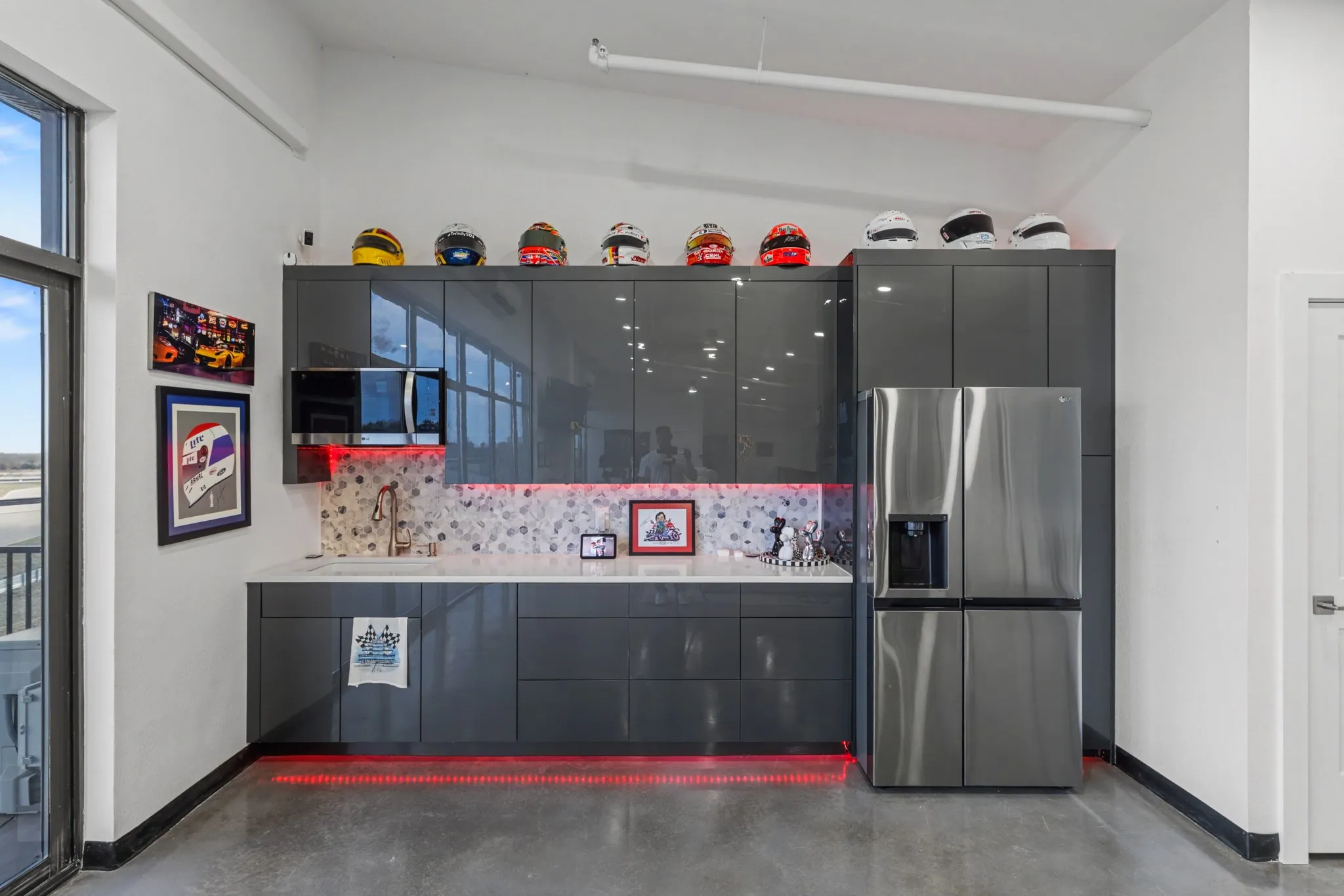 Kitchen featuring stainless steel refrigerator with ice dispenser, modern cabinets, finished concrete flooring, decorative backsplash, and light stone counters