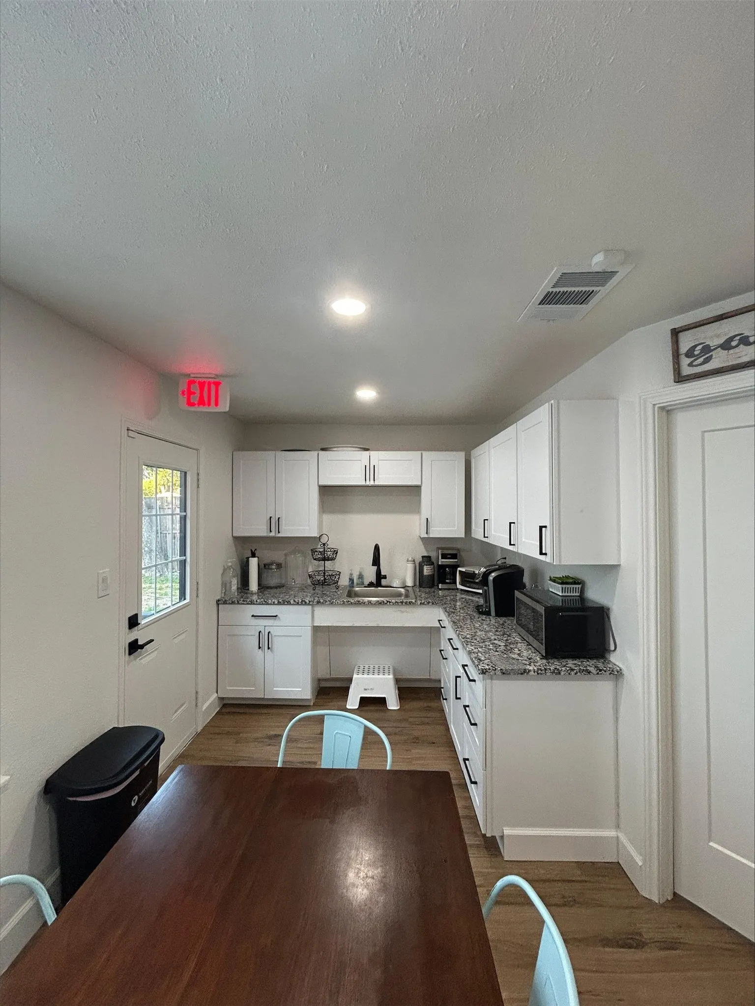 Kitchen with sink, a textured ceiling, dark wood-type flooring, white cabinetry, and light stone countertops