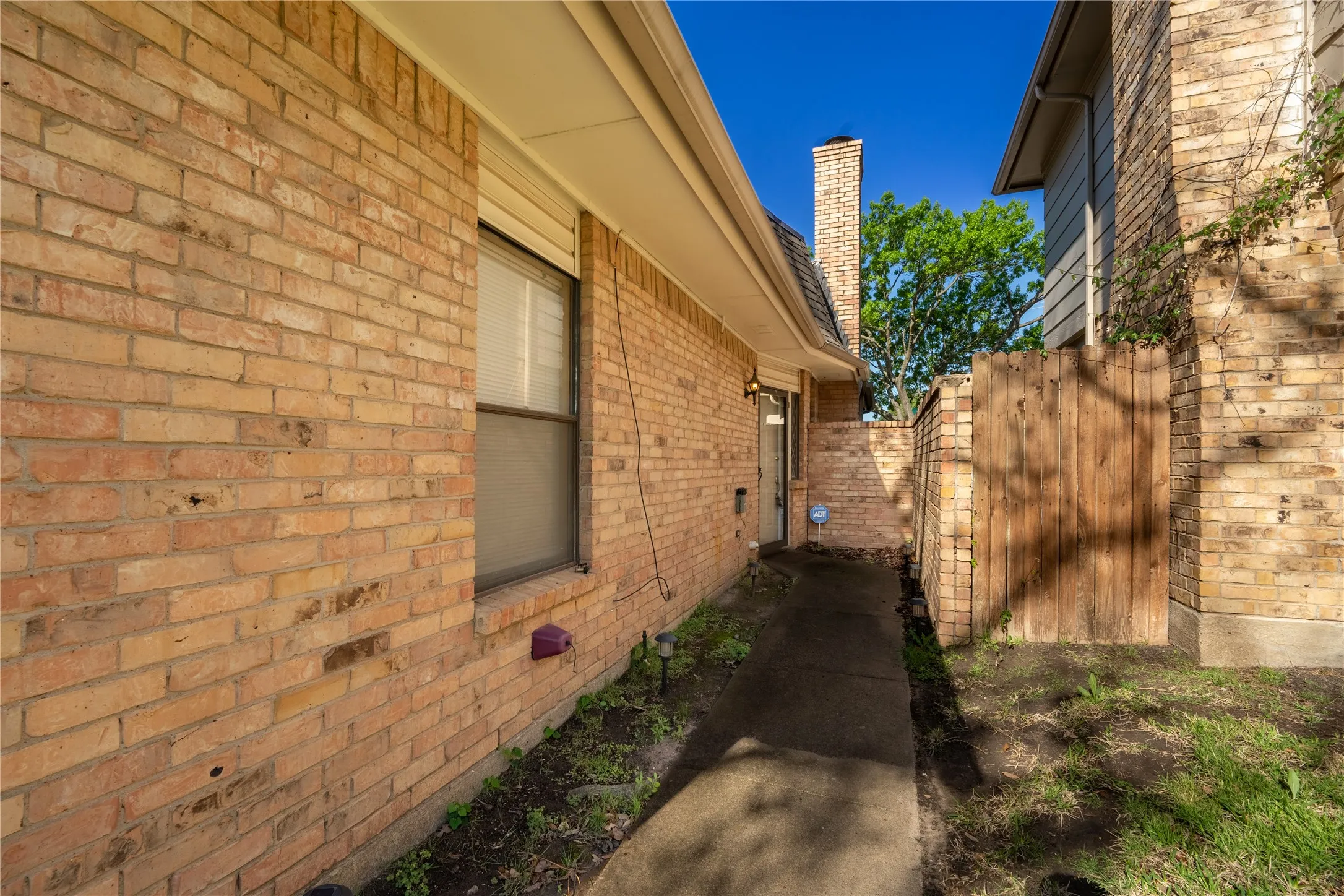 View of property exterior featuring brick siding, fence, and a chimney
