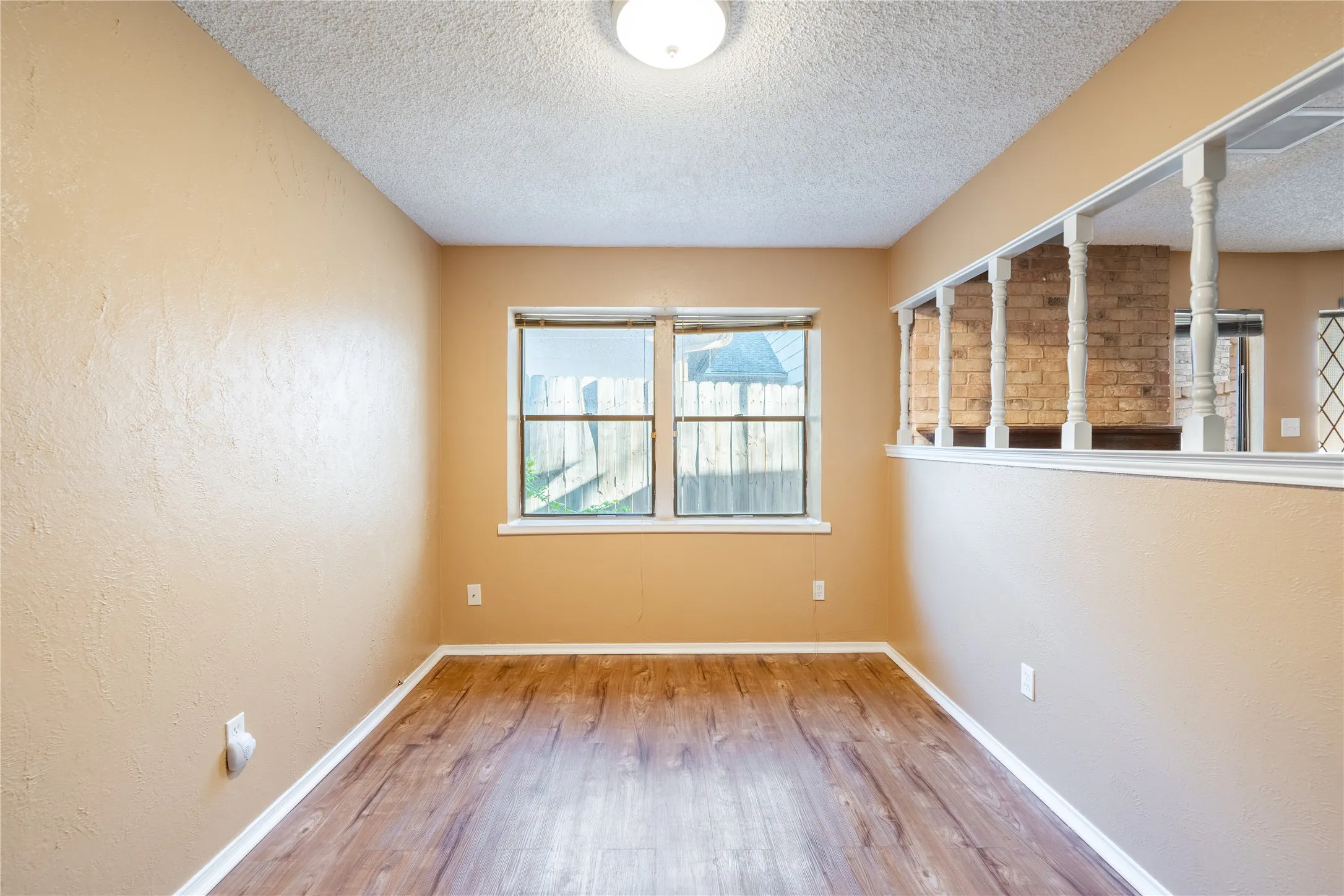 Dining room with a textured wall, baseboards, a textured ceiling, and wood finished floors