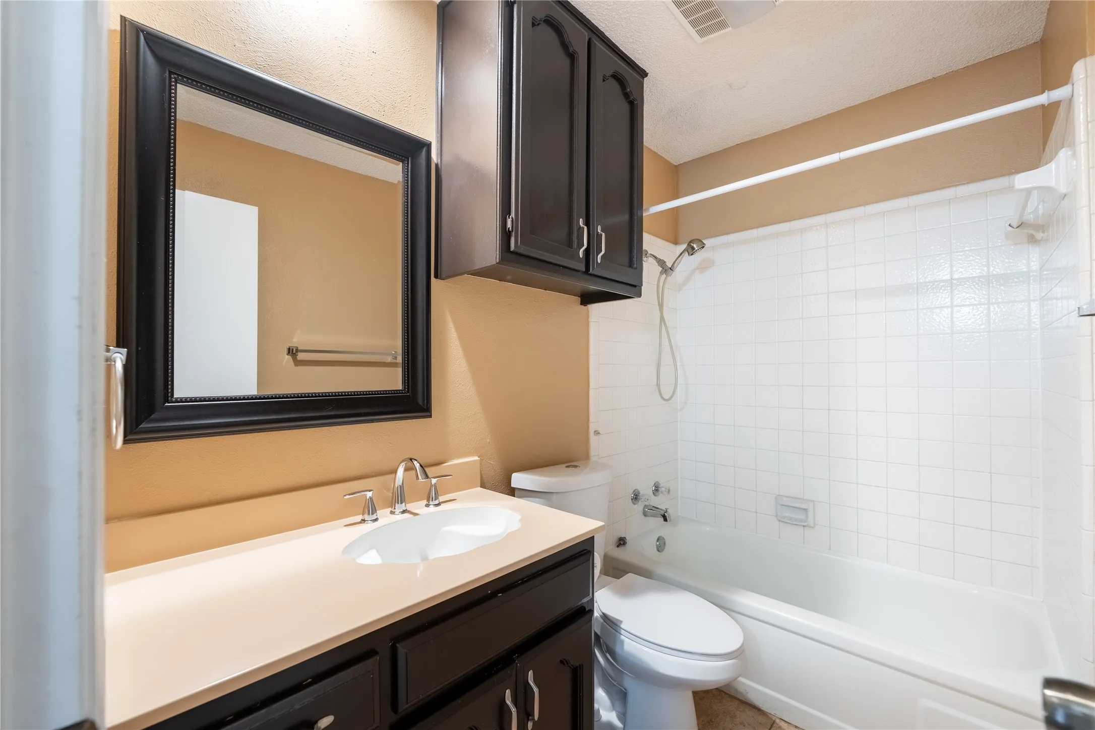 Full bath with vanity, shower / bath combination, a textured ceiling, toilet, and visible vents
