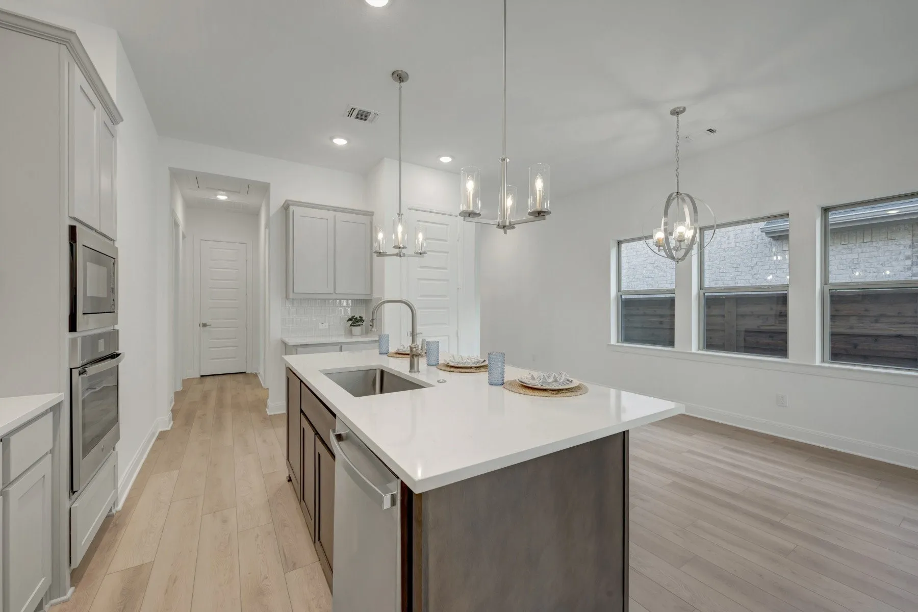 Kitchen island with an undermount sink, a white countertop, and dark wood-finish cabinetry