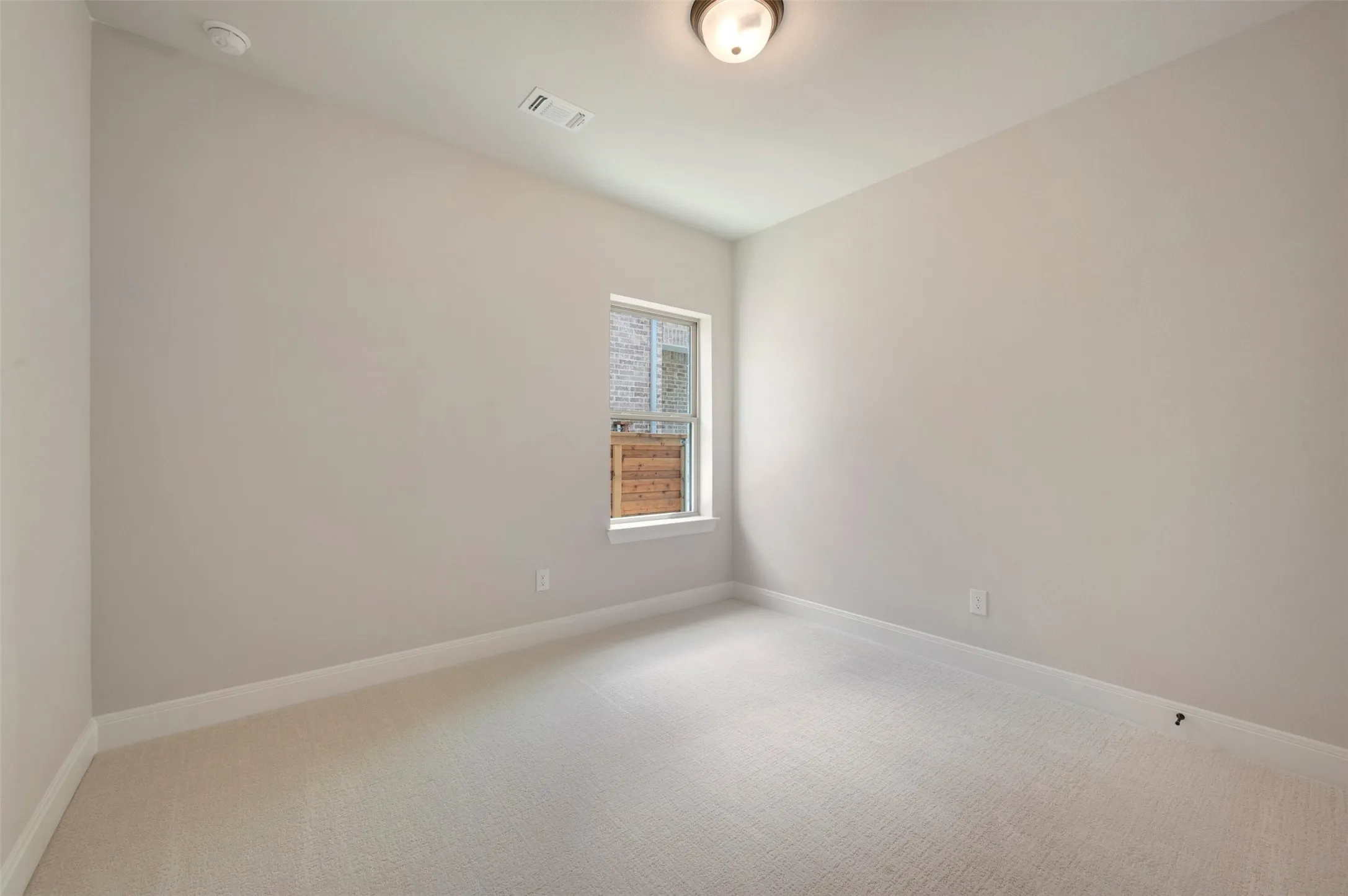Carpeted room featuring neutral wall paint, a single window, and a flush mount ceiling light fixture