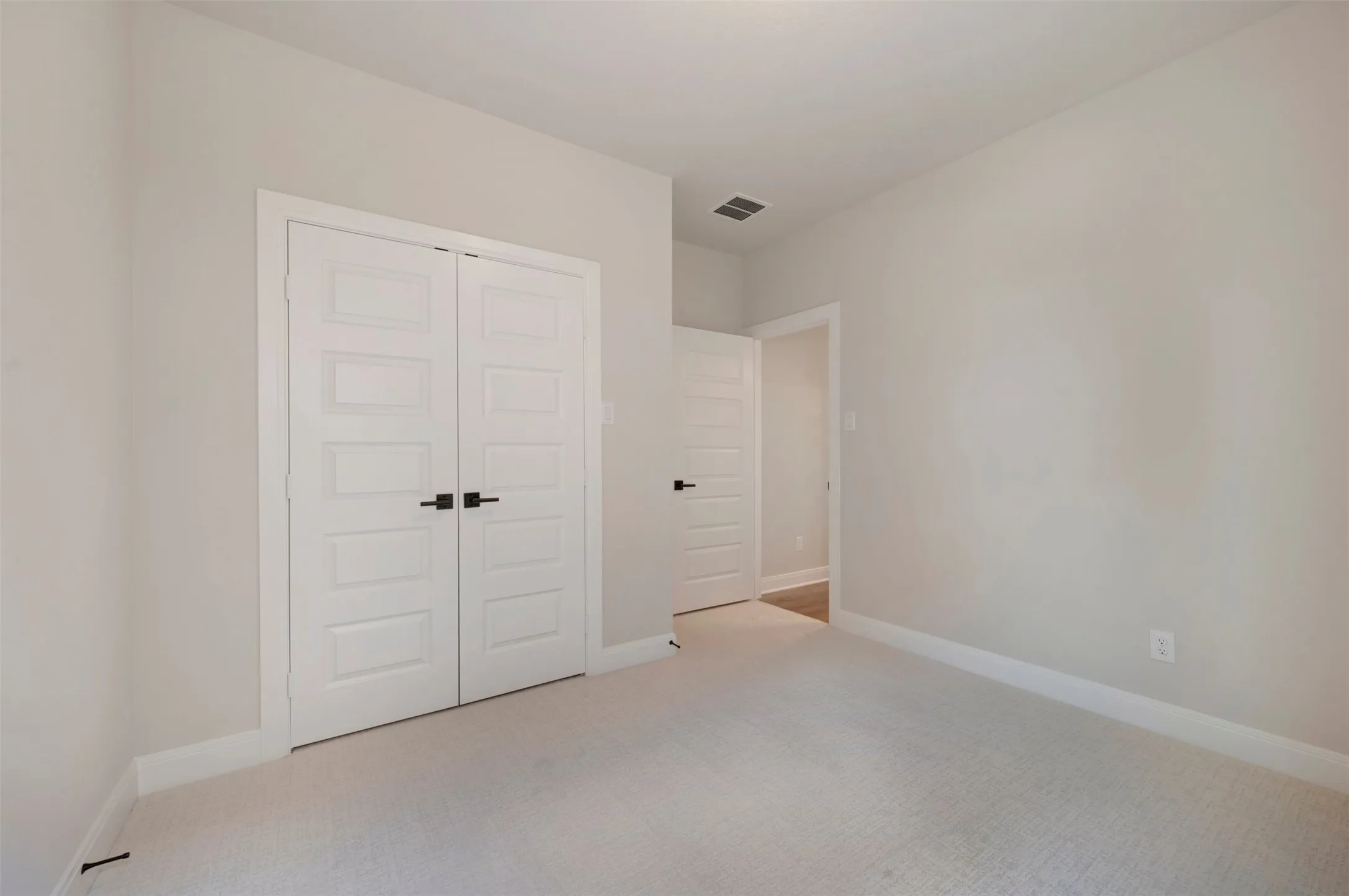 Bright room featuring light grey walls, white trim, and a plush light-colored carpet
