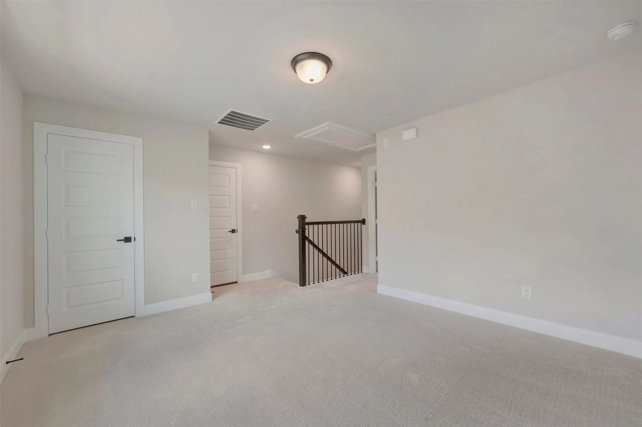 Spacious upper-level room featuring neutral carpet flooring, recessed ceiling lighting, and multiple white panel doors providing access to adjoining spaces