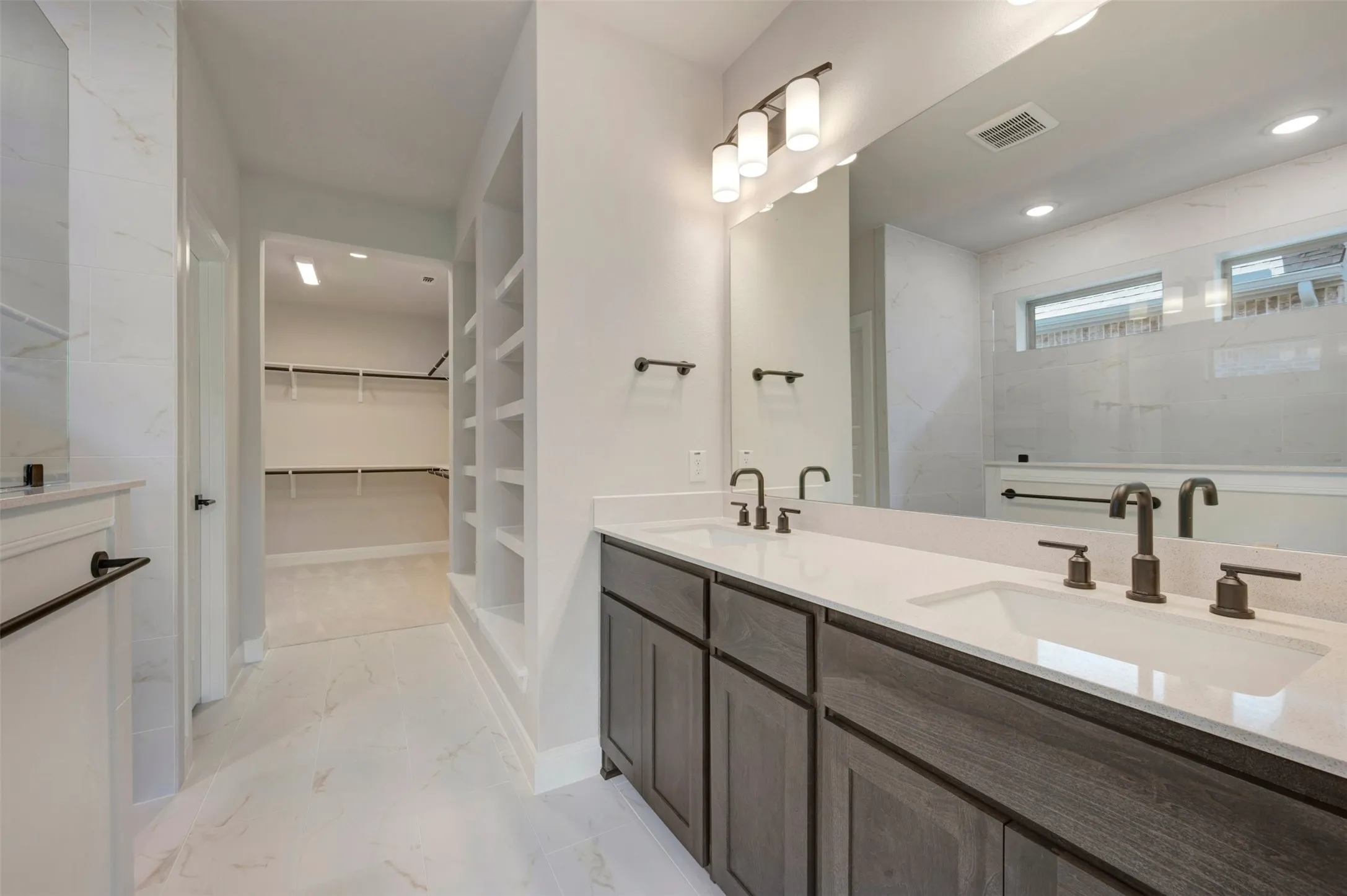 Spa-inspired primary bathroom featuring a dual-sink vanity with wood-finish cabinetry, white quartz countertops, and matte black faucet fixtures