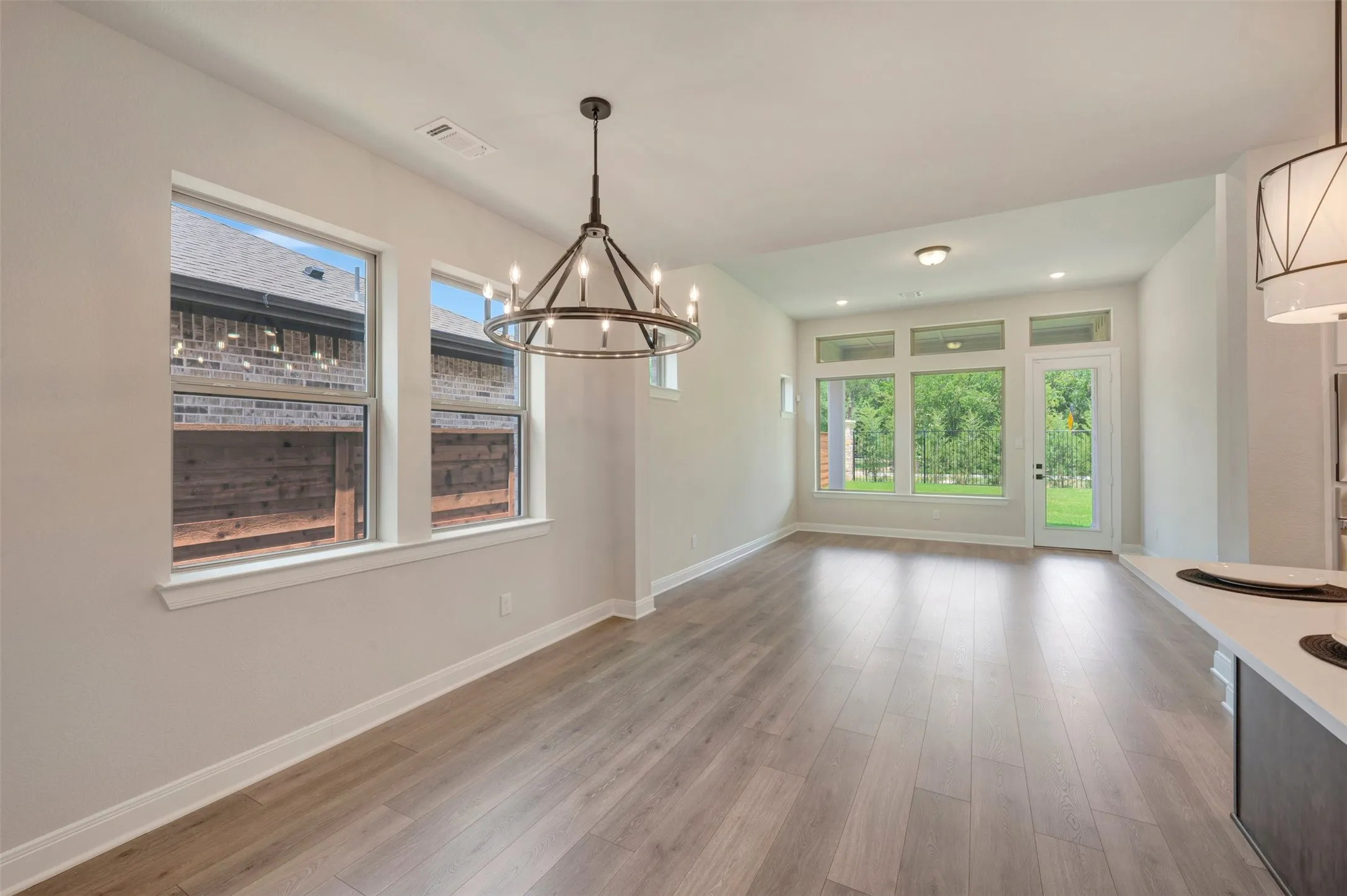 Open concept living space featuring wood-finish flooring, a contemporary chandelier, multiple large windows, recessed lighting, and a white countertop