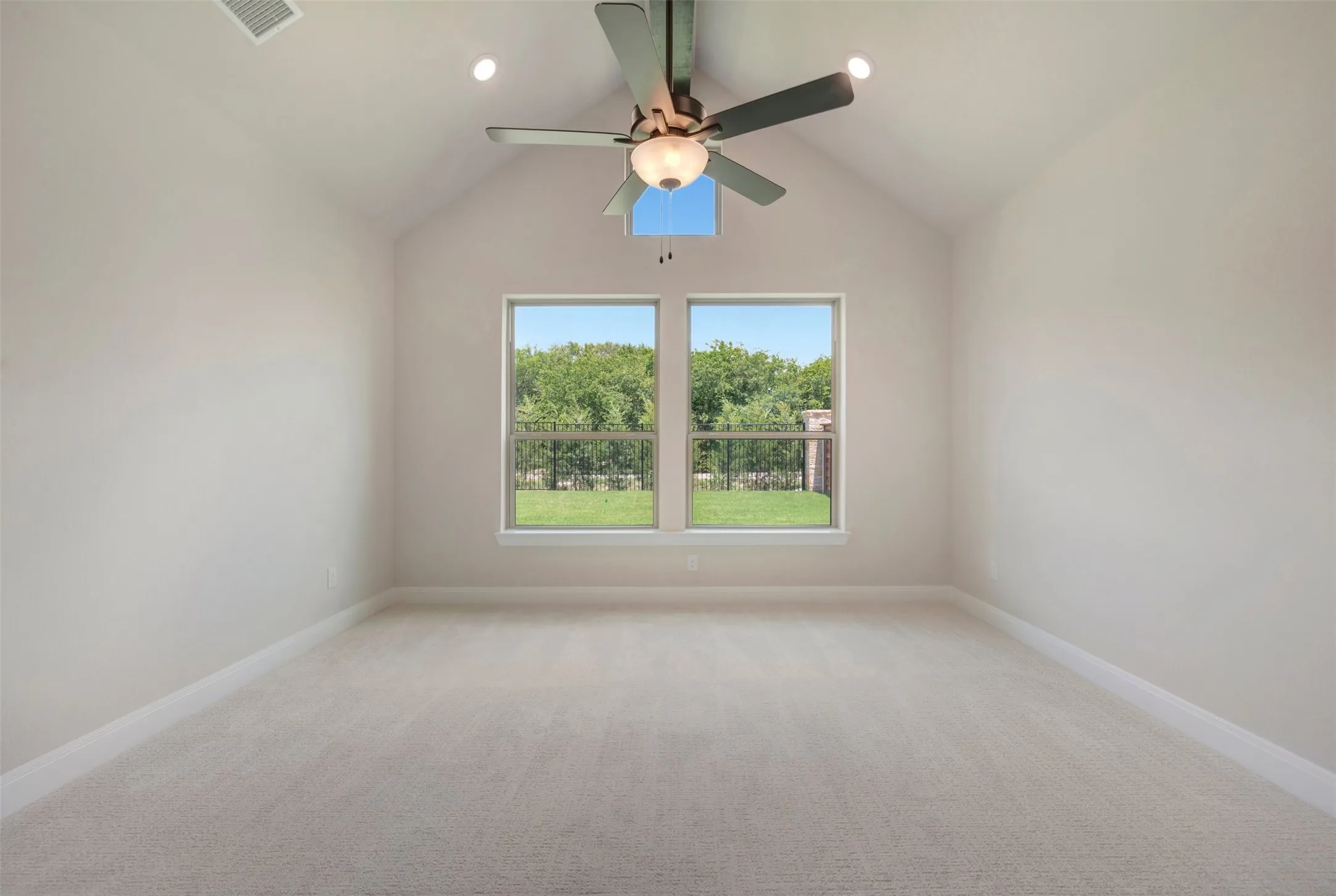 Vaulted ceiling room with light-colored carpet flooring