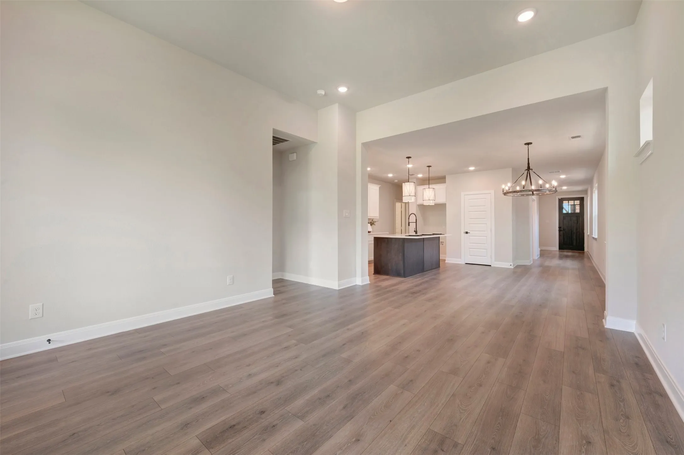 Expansive living area featuring light wood-finish flooring, recessed lighting, and a neutral wall palette