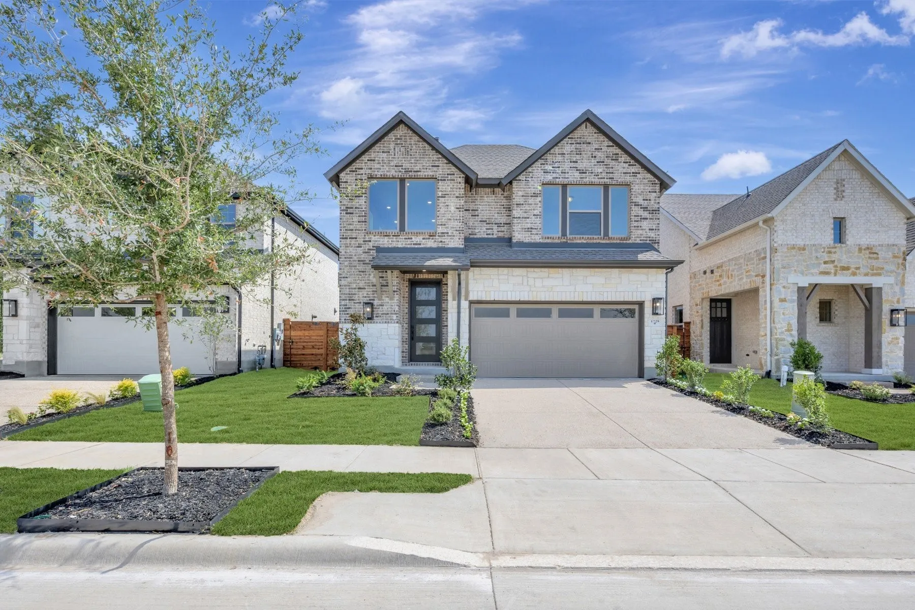 Two-story residence featuring a stone and siding exterior, a two-car garage, and a concrete driveway