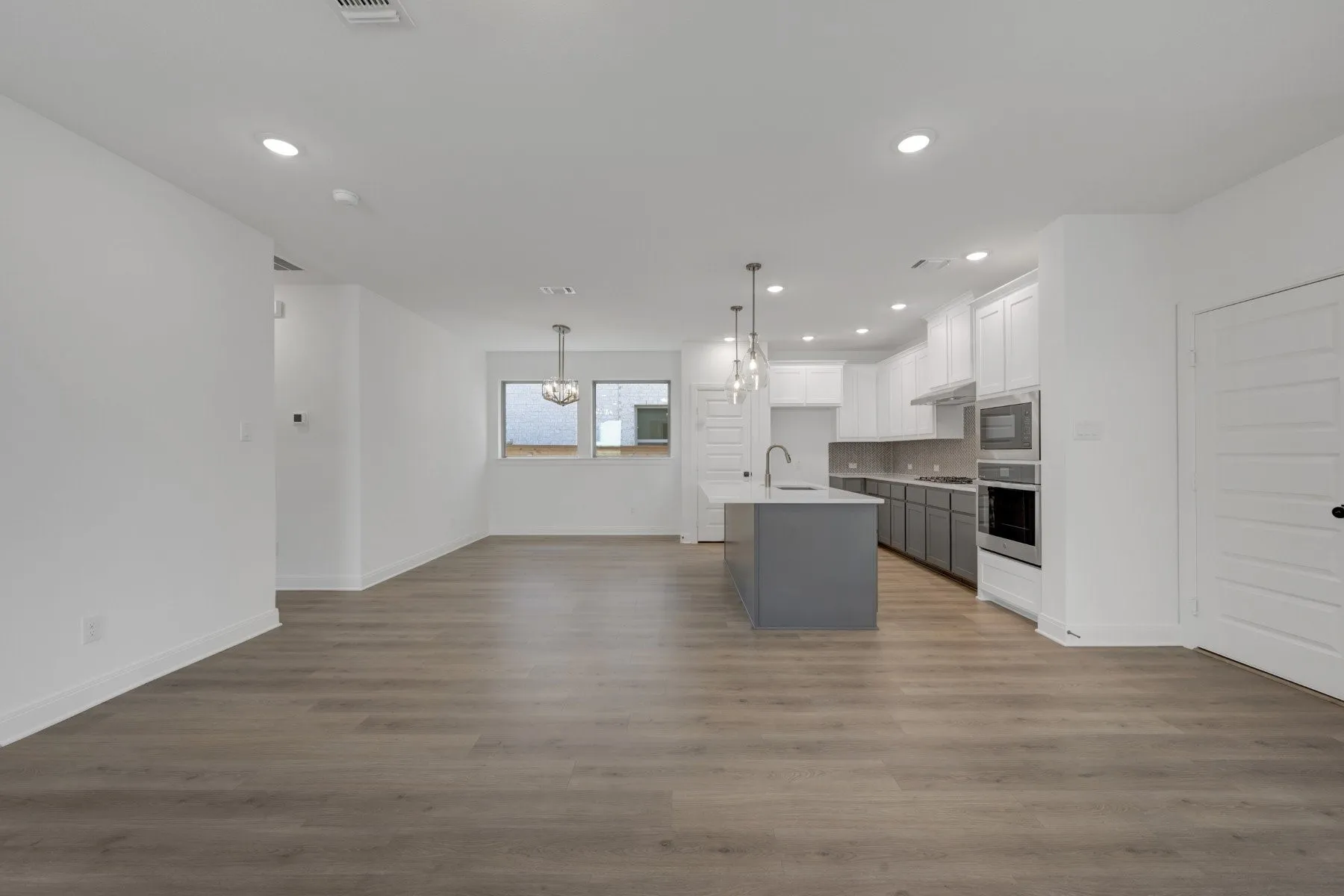Open-concept living space featuring wood-finish flooring, recessed lighting, and a modern kitchen