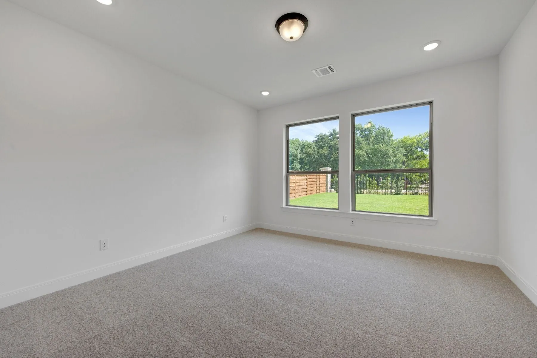 Spacious room featuring two large windows, recessed ceiling lighting, a flush mount ceiling fixture, plush carpet flooring, and white baseboards
