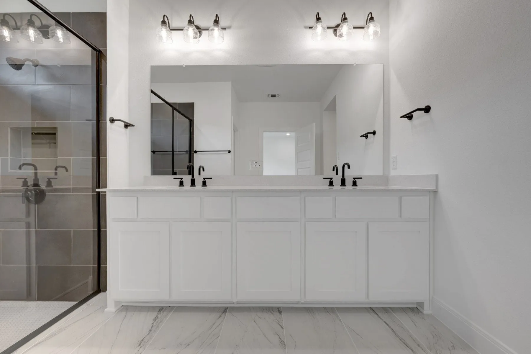 Dual vanity with white cabinetry, light-toned countertops, and matte black fixtures