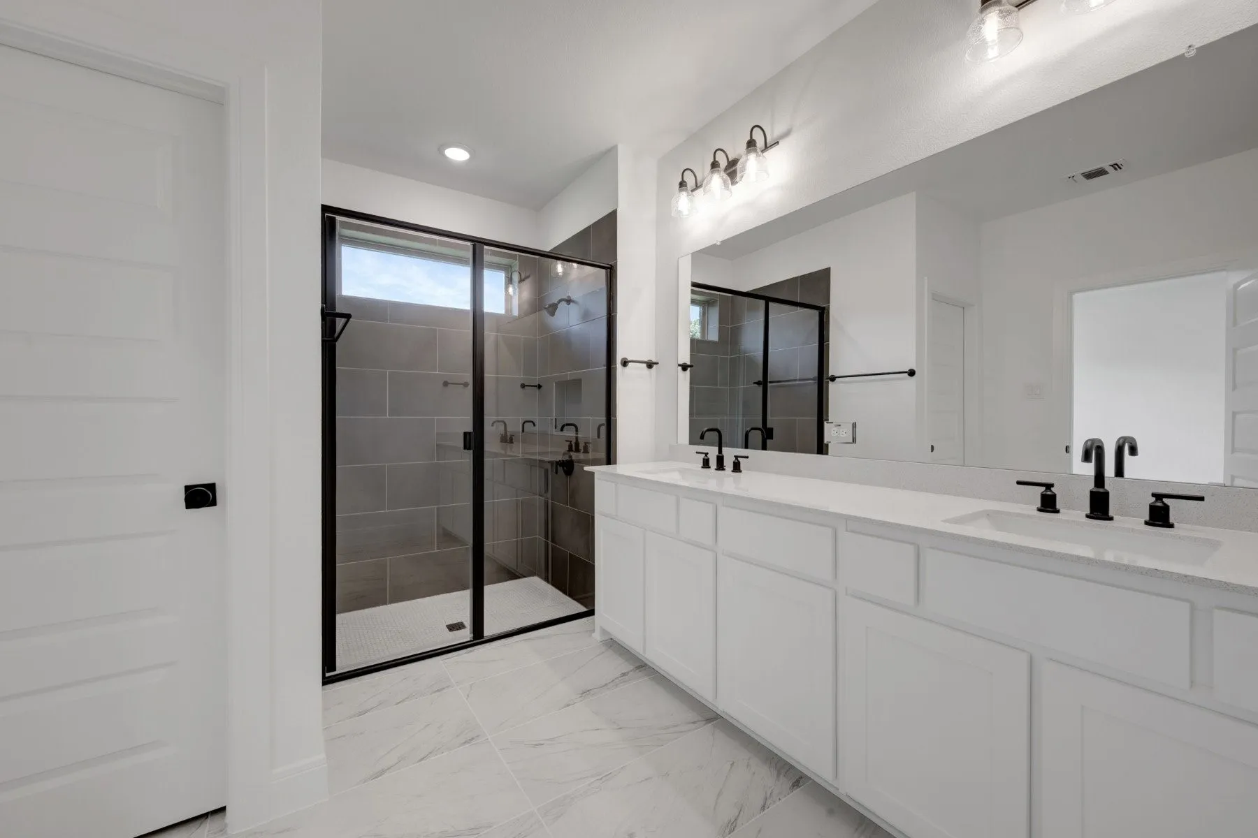 Spa-inspired primary bathroom featuring a dual-sink vanity with white cabinetry, white quartz countertops, and matte black fixtures
