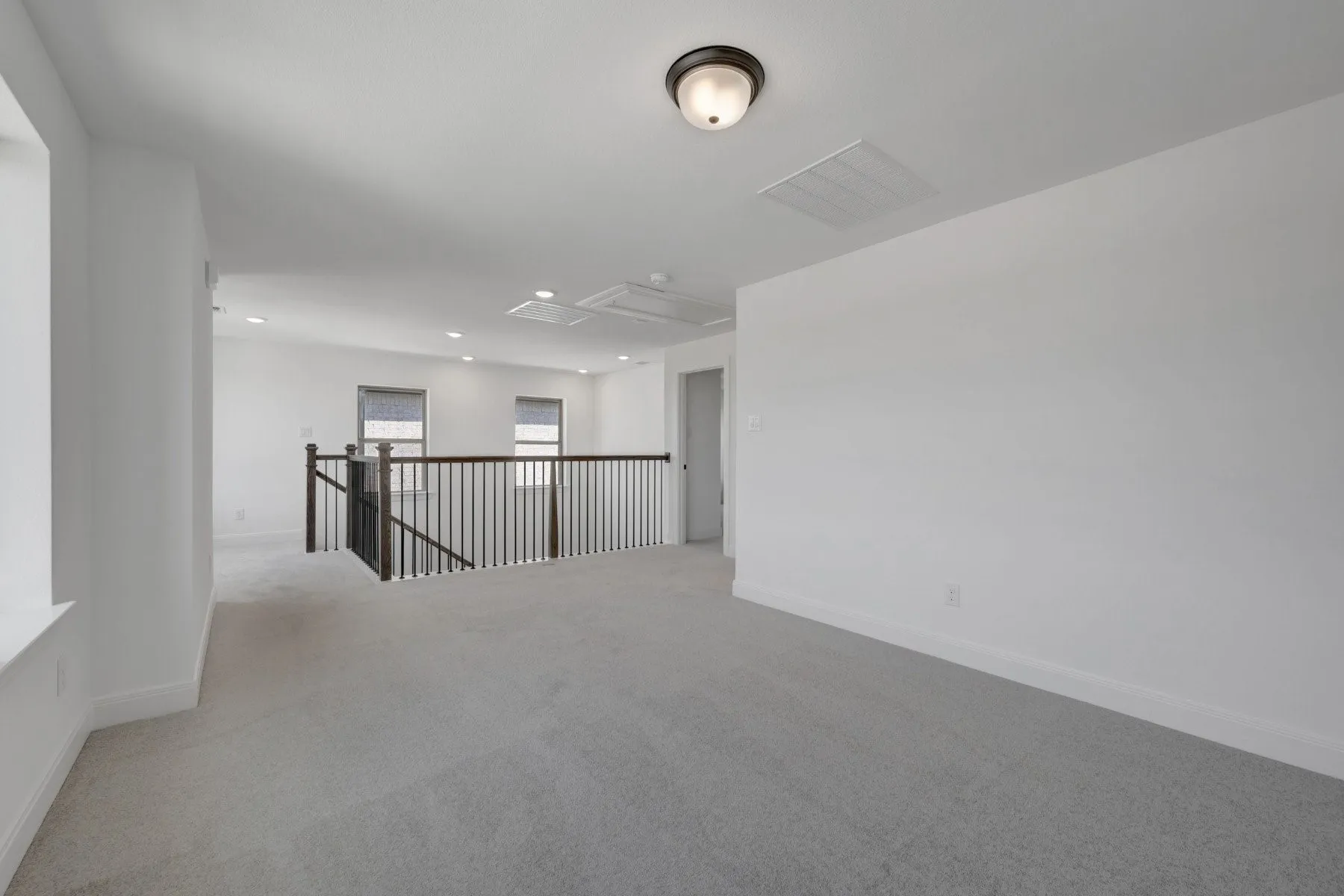 Spacious upper-level loft featuring neutral carpet flooring, clean white walls, and abundant natural light from multiple windows
