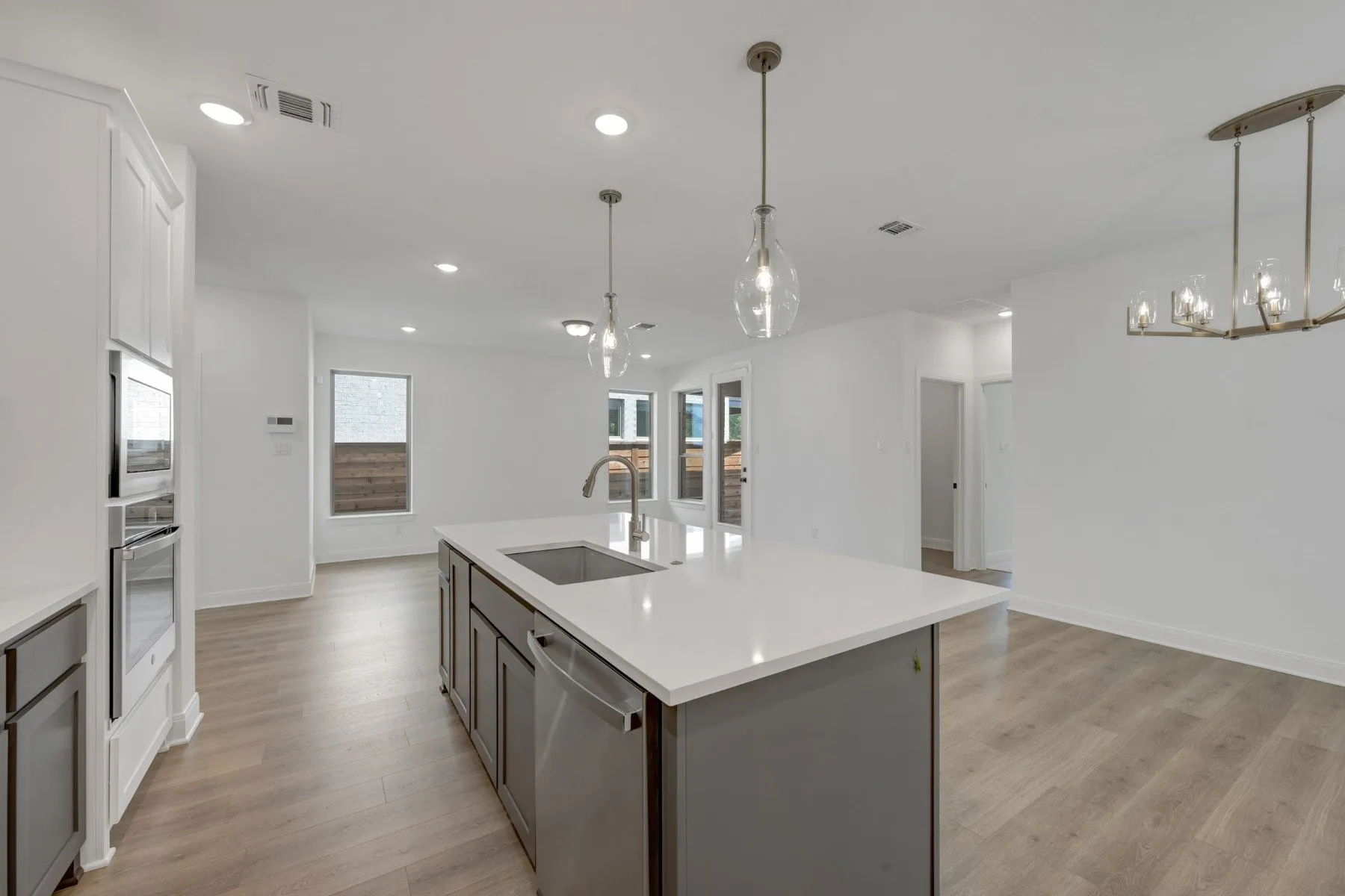 Modern kitchen island with a built-in stainless steel sink and dishwasher, complemented by recessed lighting and pendant fixtures