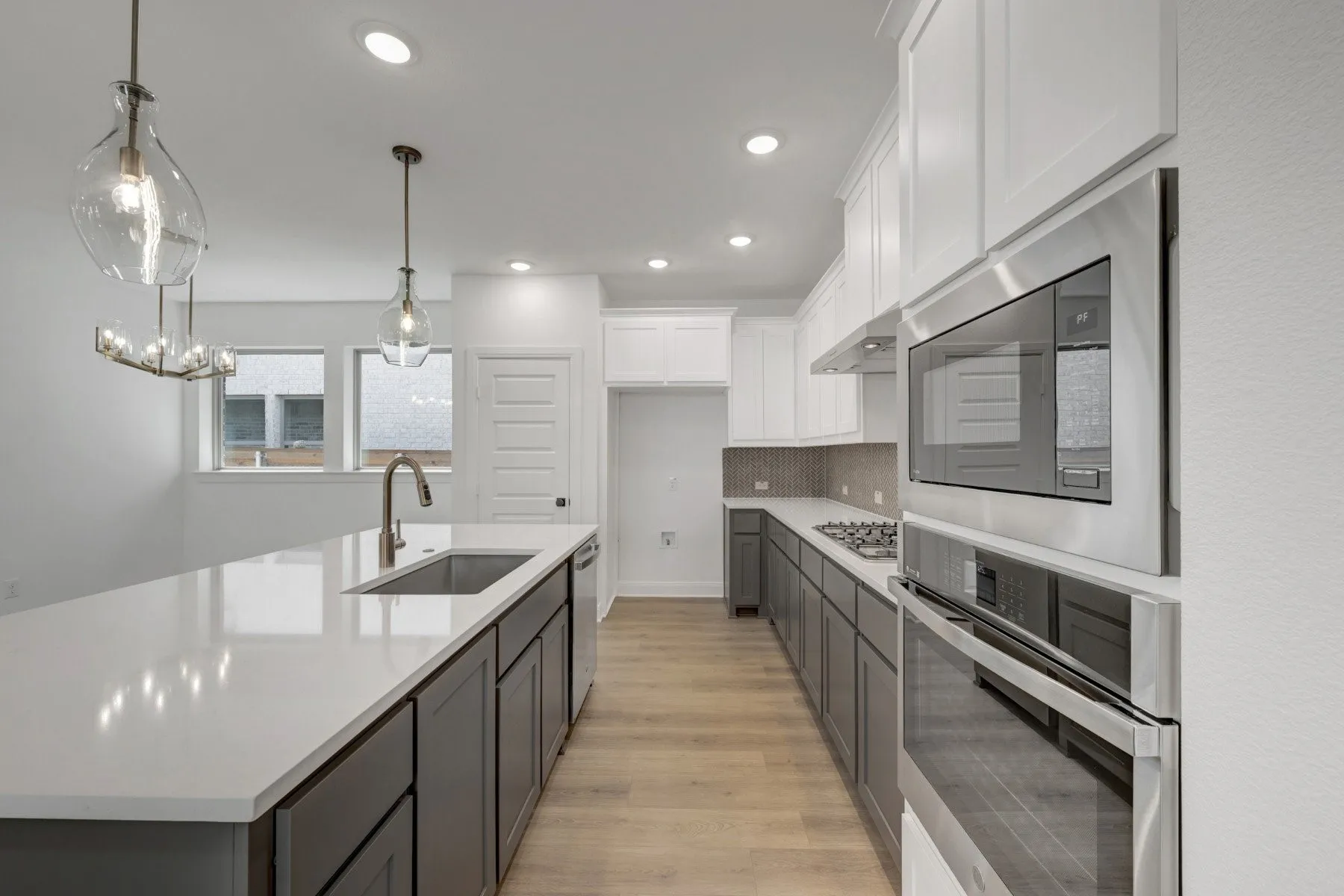 Modern kitchen featuring a large island with an undermount sink, a gooseneck faucet, and light-toned countertops