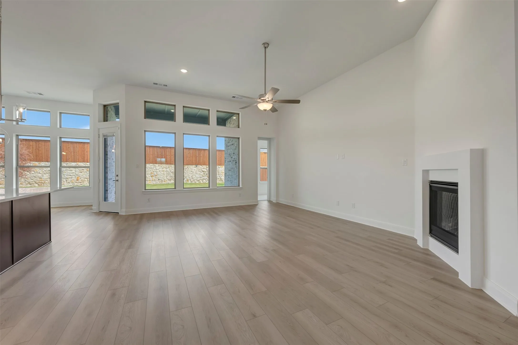 Vaulted ceiling, recessed lighting, wood-finish flooring, built-in fireplace, and expansive windows