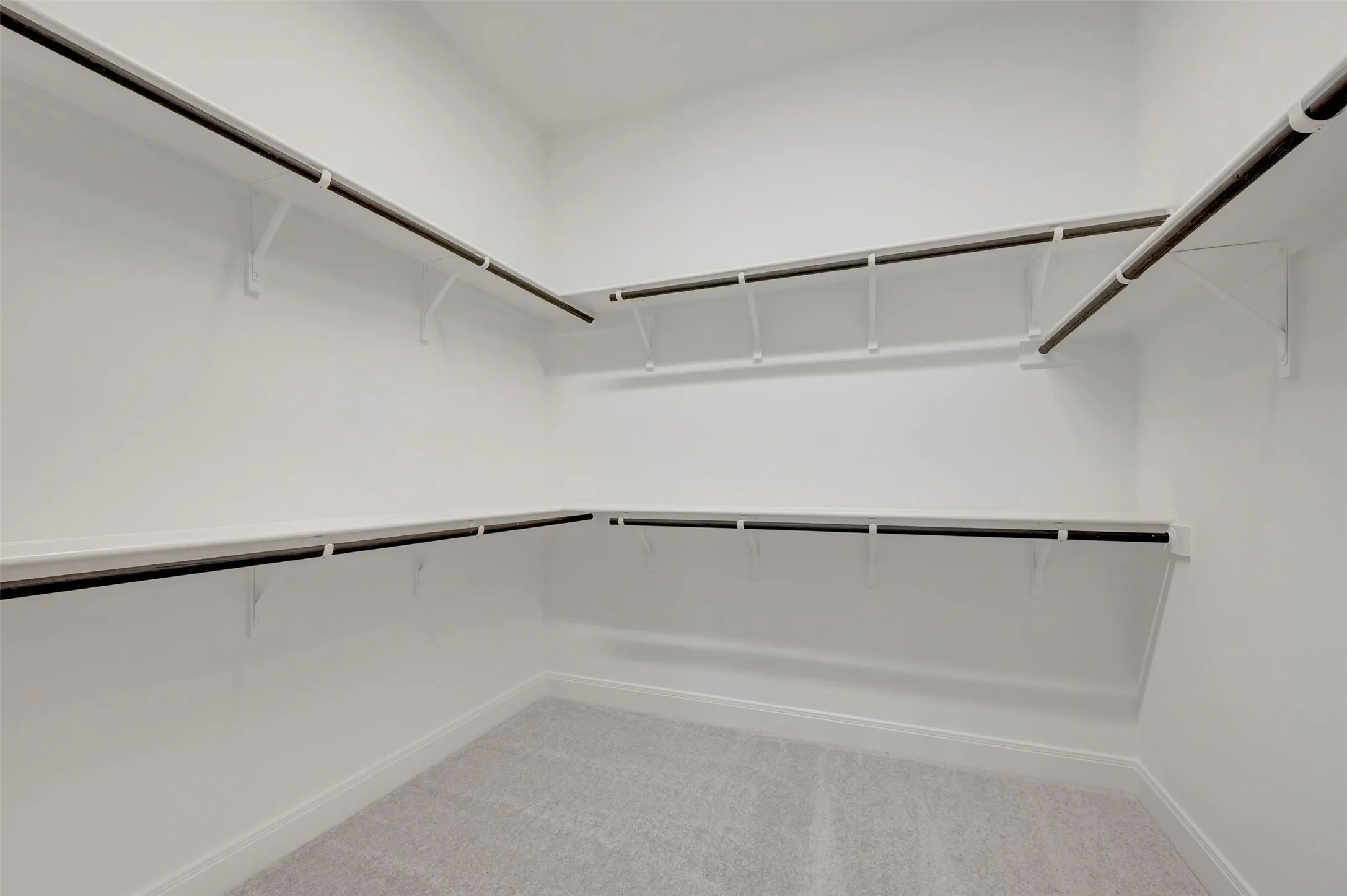 White wall-mounted shelving with integrated hanging rods, providing extensive storage