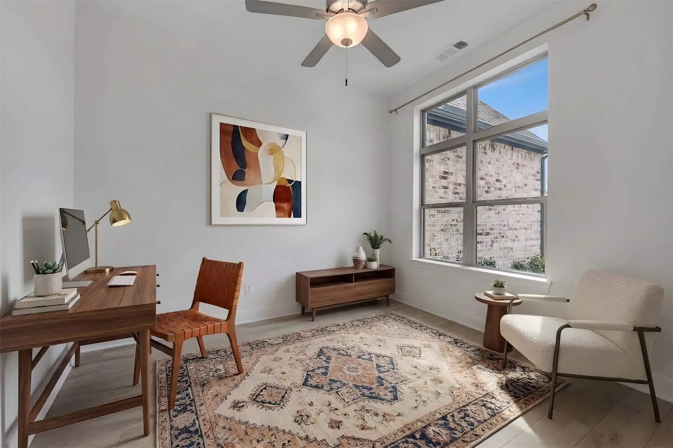Light wood-finish flooring, ceiling fan with integrated lighting, and a large multi-pane window
