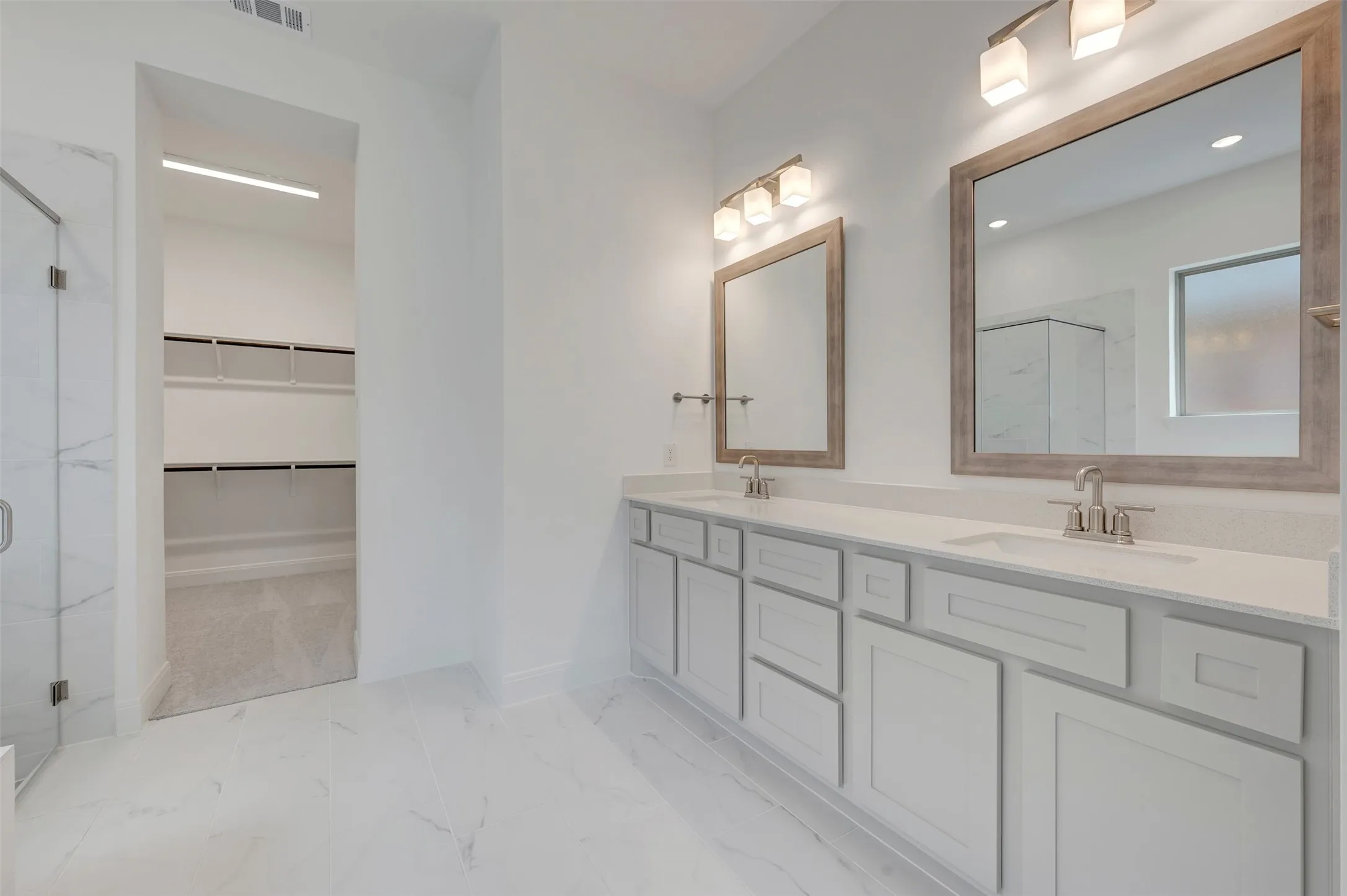 Dual vanity with light gray cabinetry and integrated sinks, complemented by framed mirrors with sconce lighting